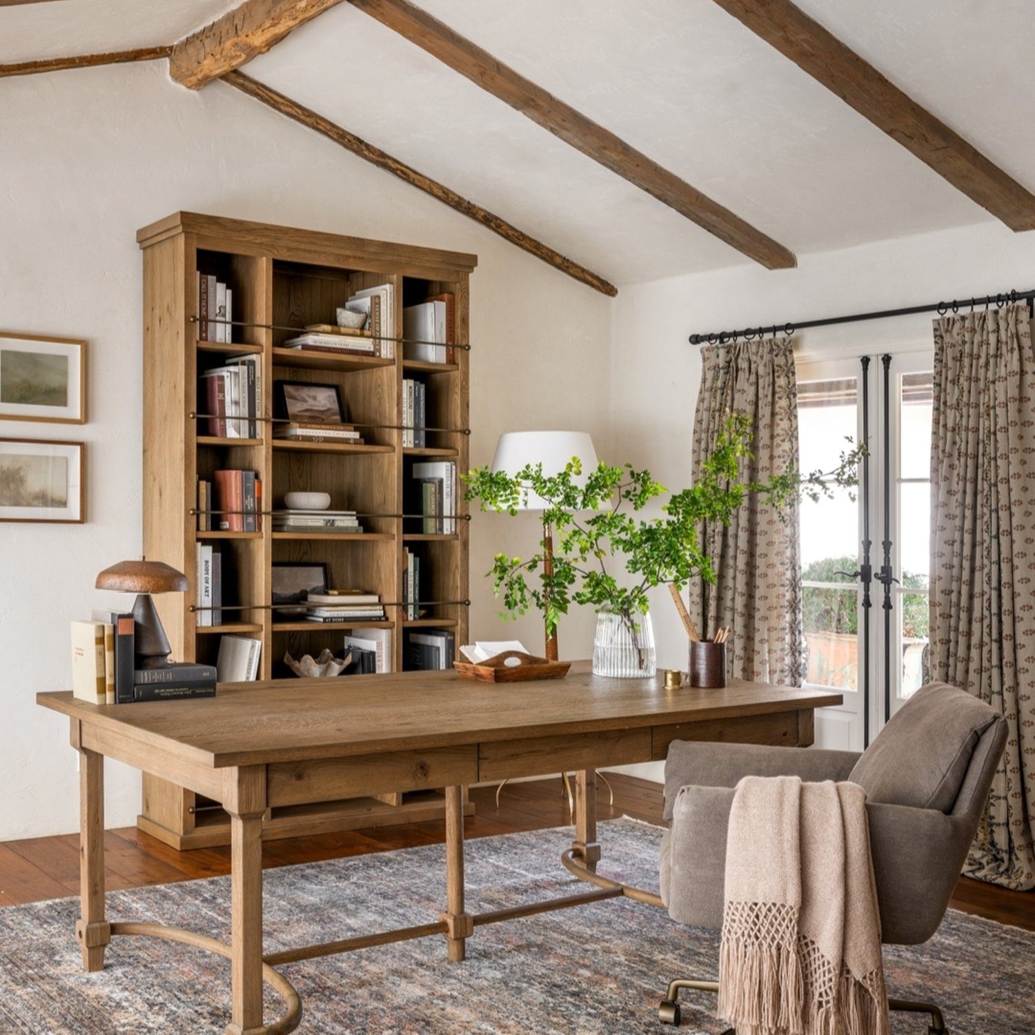 A cozy home office featuring exposed wooden beams and a warm color palette