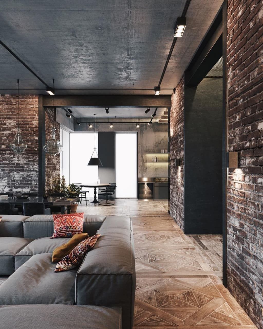 A stylish and modern living space featuring a combination of rustic brick walls, sleek grey concrete ceiling, and herringbone-patterned wooden flooring.