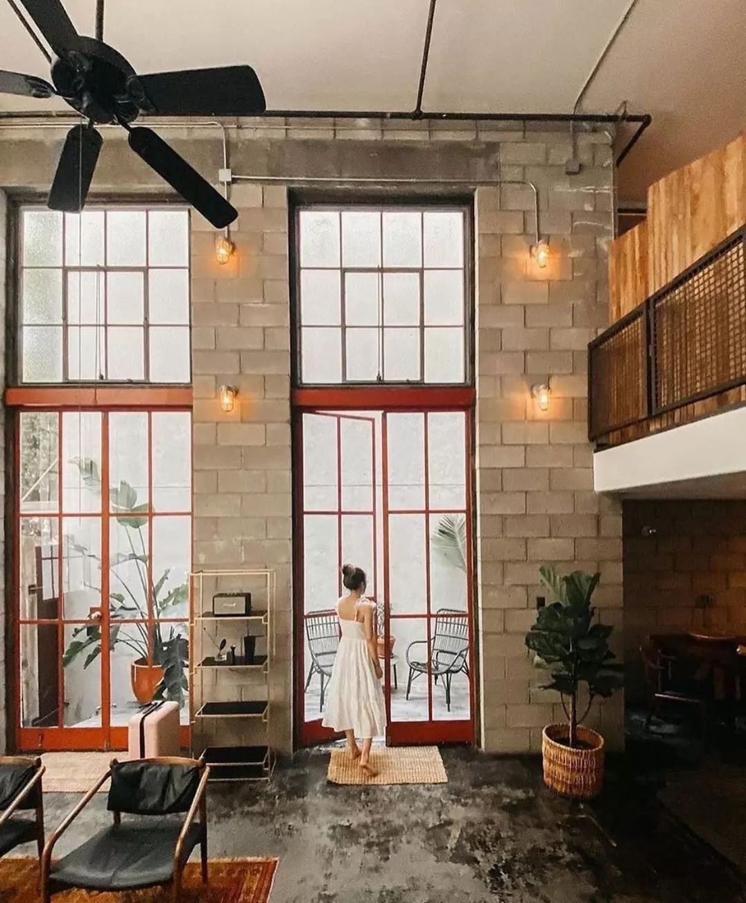 A modern industrial-style living room with high ceilings and large windows