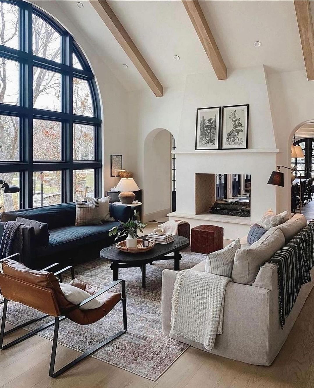 A spacious and contemporary living room with a soaring arched window