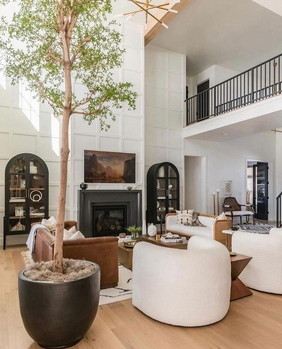 A spacious living room blending modern and rustic elements with a towering indoor tree.