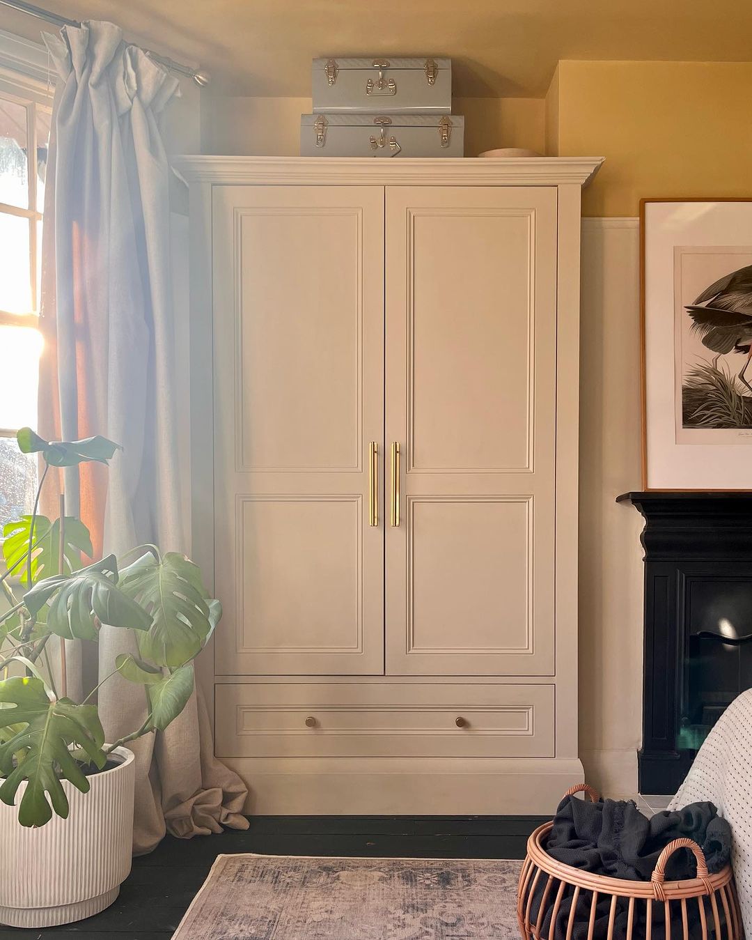 A neatly organized room with a cream-colored wardrobe