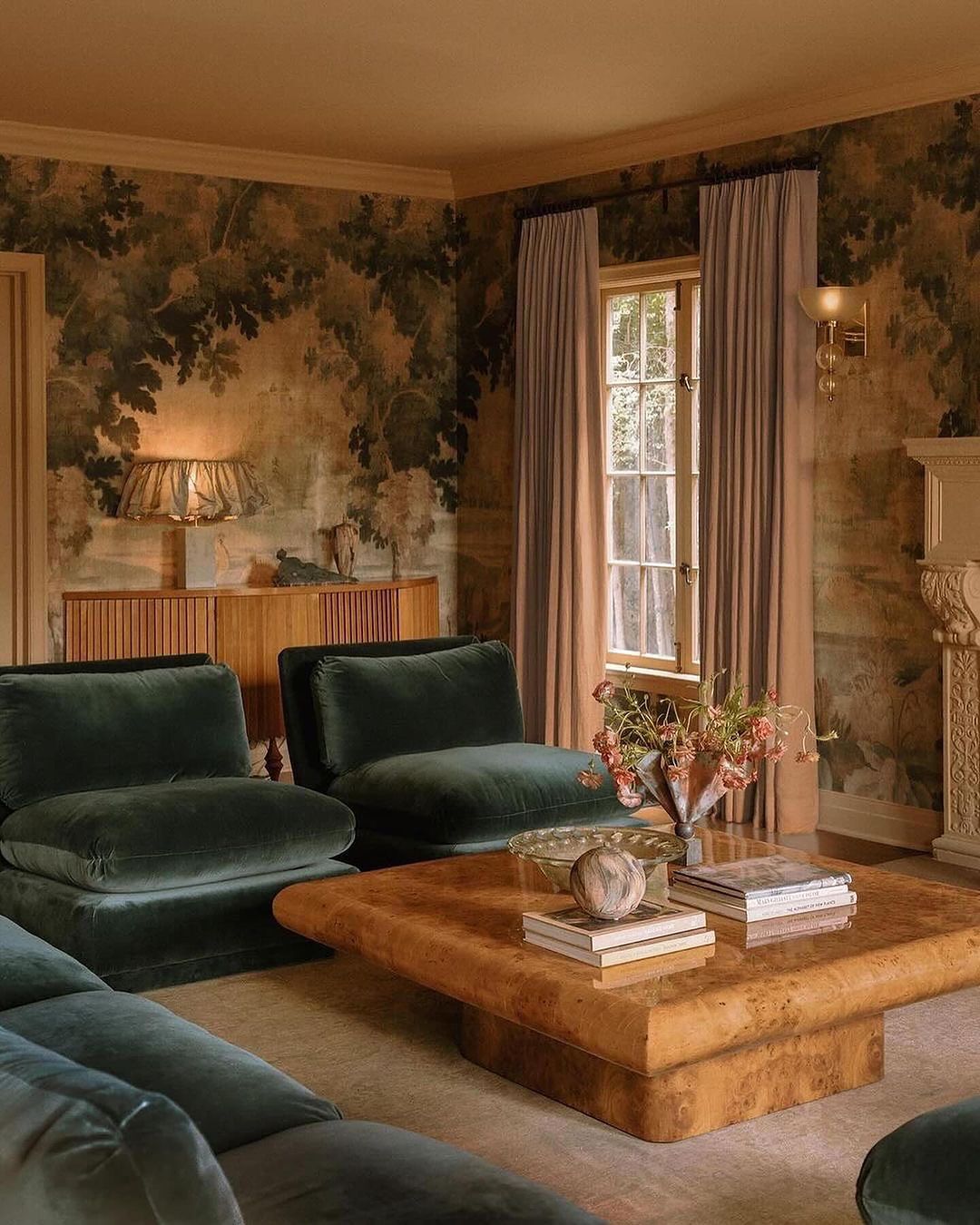 A warm and inviting living room with plush green velvet armchairs and a large burl wood coffee table