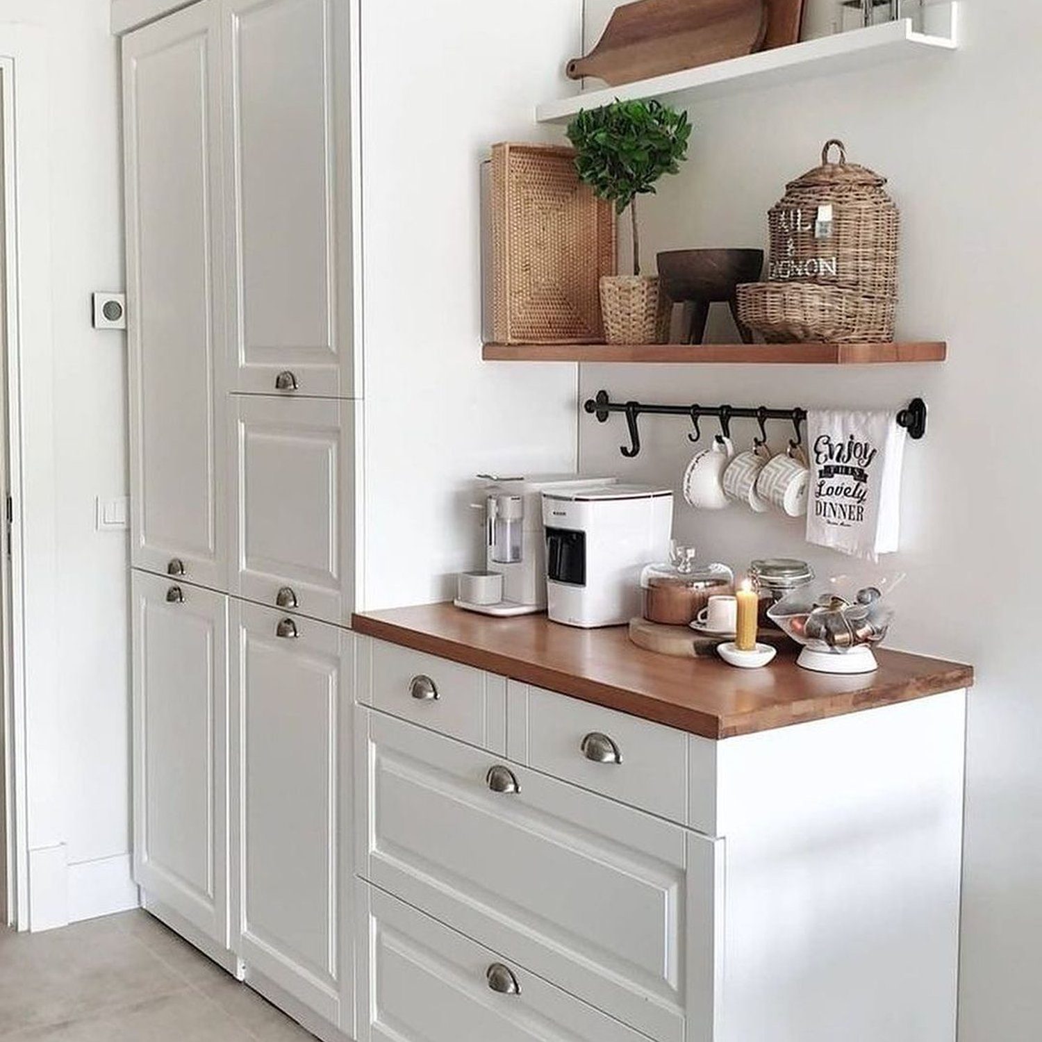 A neatly organized kitchen corner with white cabinetry, wooden countertops, and modern appliances