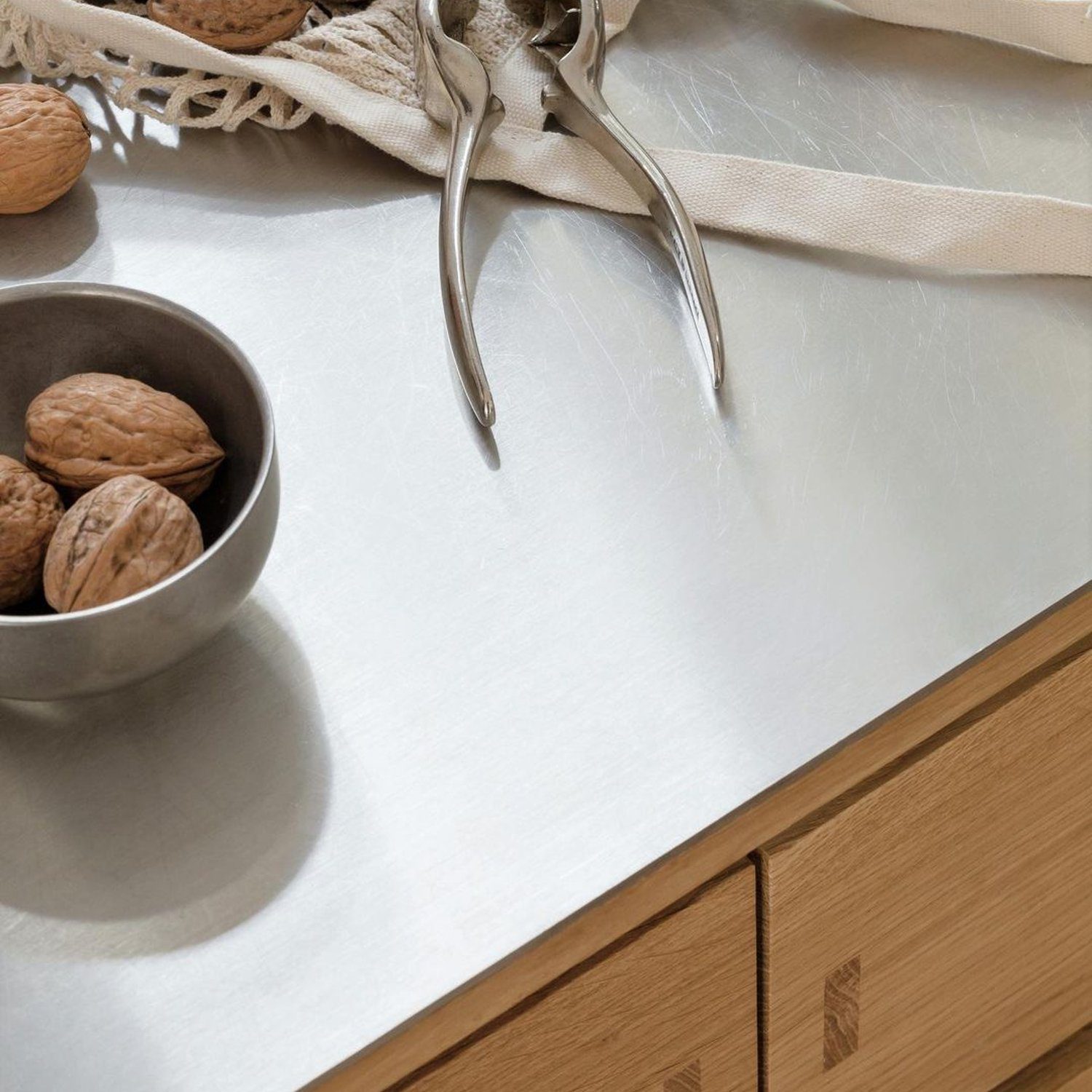 A neatly organized kitchen corner featuring a selection of walnuts in a small bowl and an elegant nutcracker on the countertop.