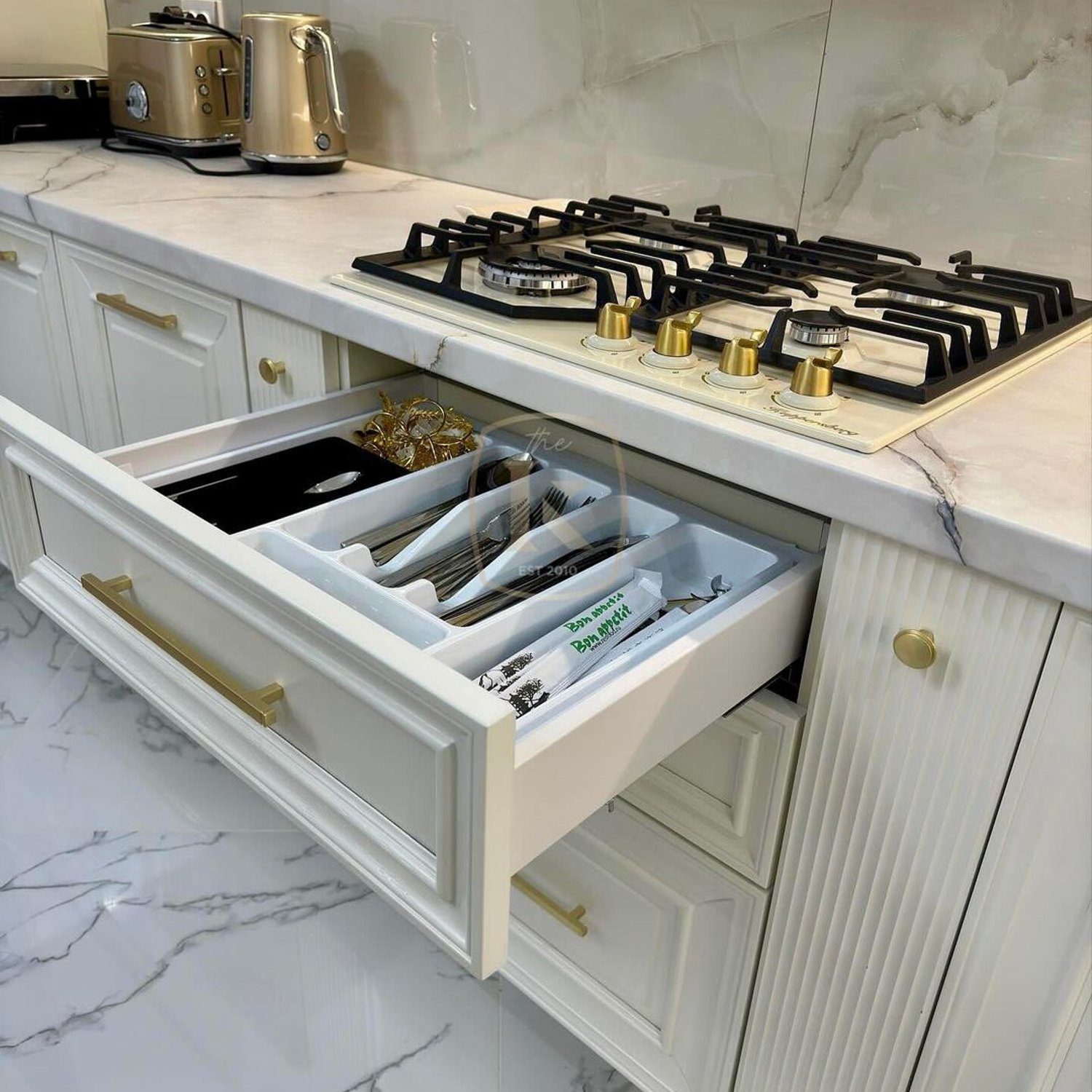 A sleek and well-organized kitchen featuring a modern gas stove and an innovative utensil drawer