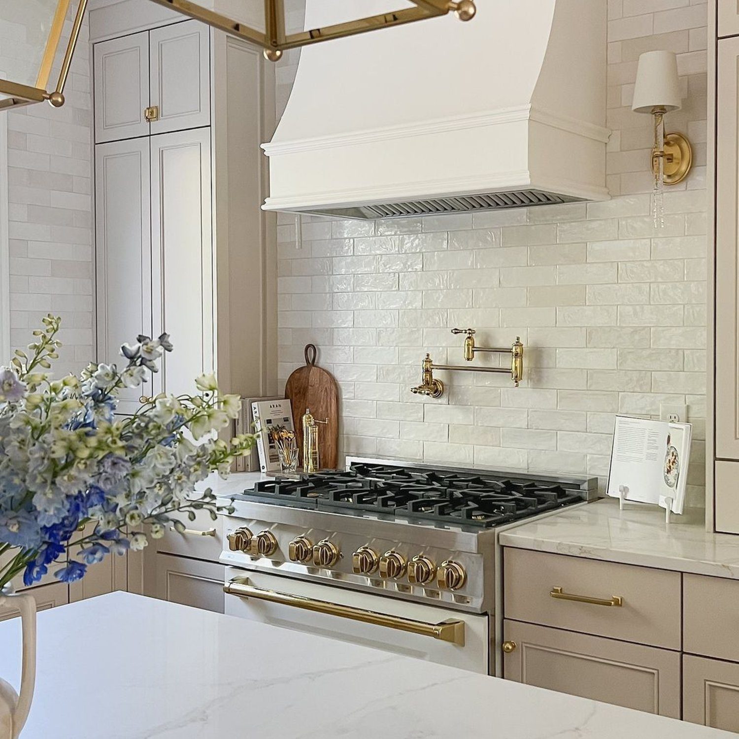 Elegant beige-toned kitchen featuring gold accents, a marble countertop, and a classic subway tile backsplash