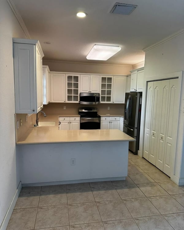 A sleek and modern kitchen featuring white cabinetry, stainless steel appliances, and a neutral backsplash