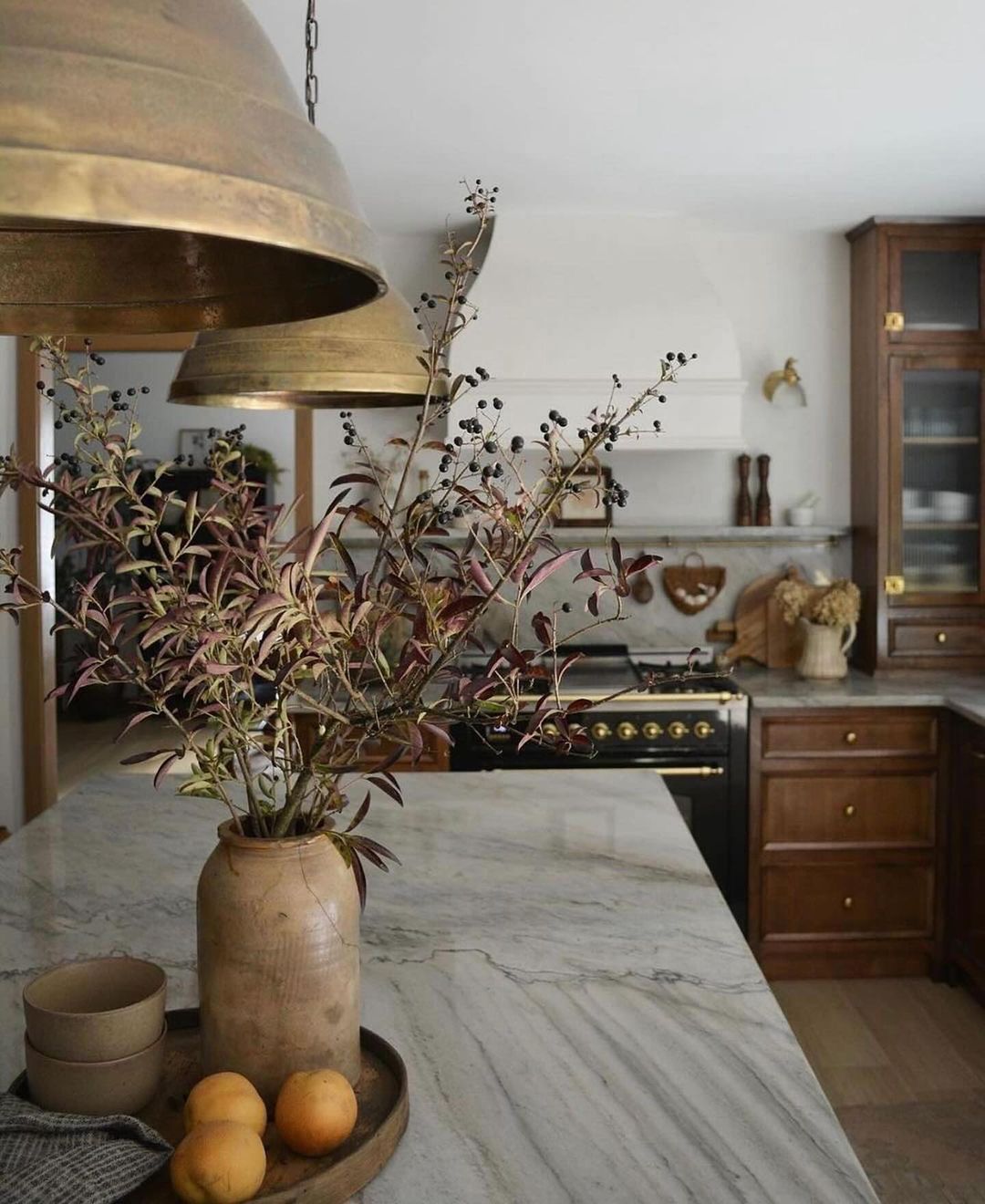 A kitchen with a mix of rich wooden textures and marble surfaces