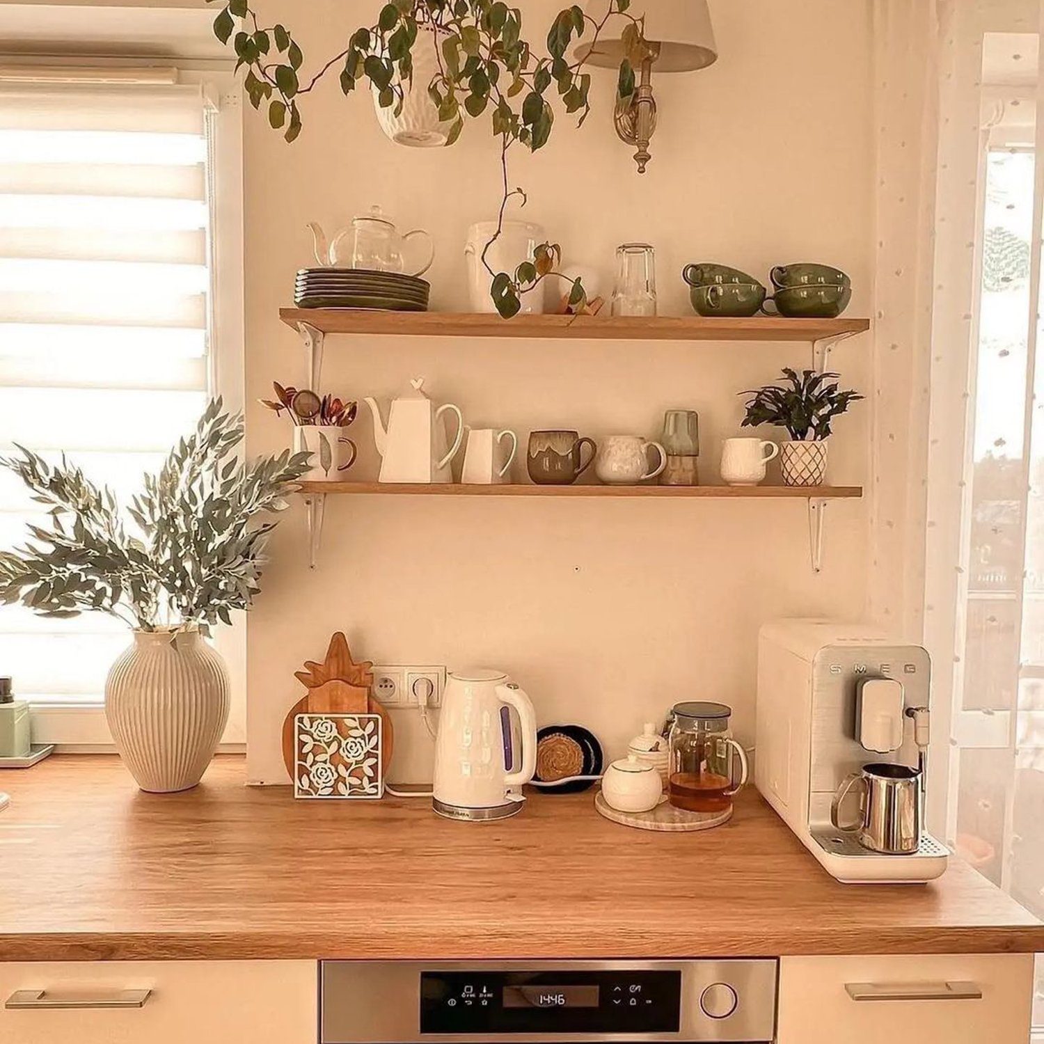 A neatly organized kitchen counter with wooden shelves displaying ceramics and plants