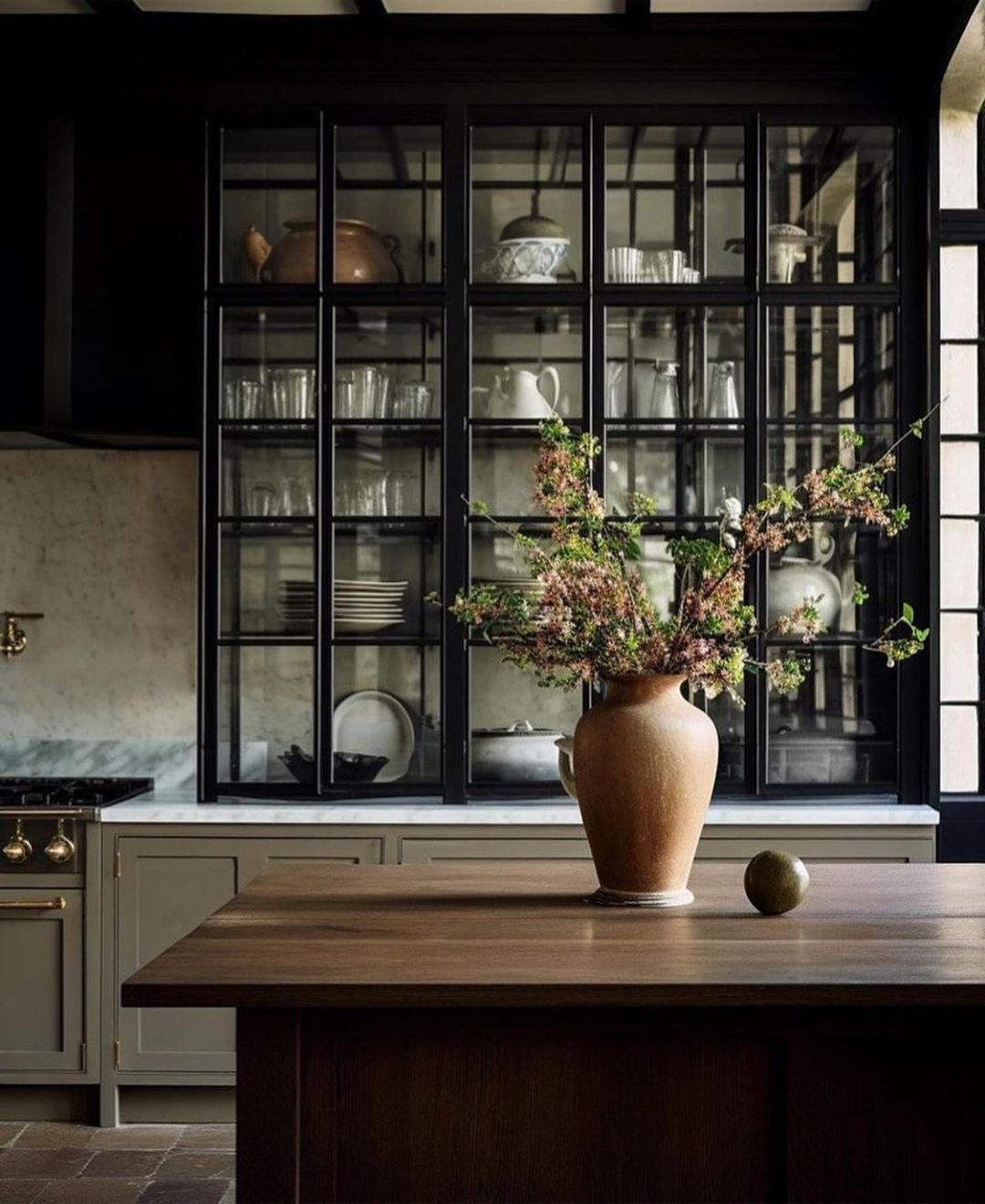 A sophisticated kitchen featuring a dark-framed glass cabinet filled with neatly arranged dishware