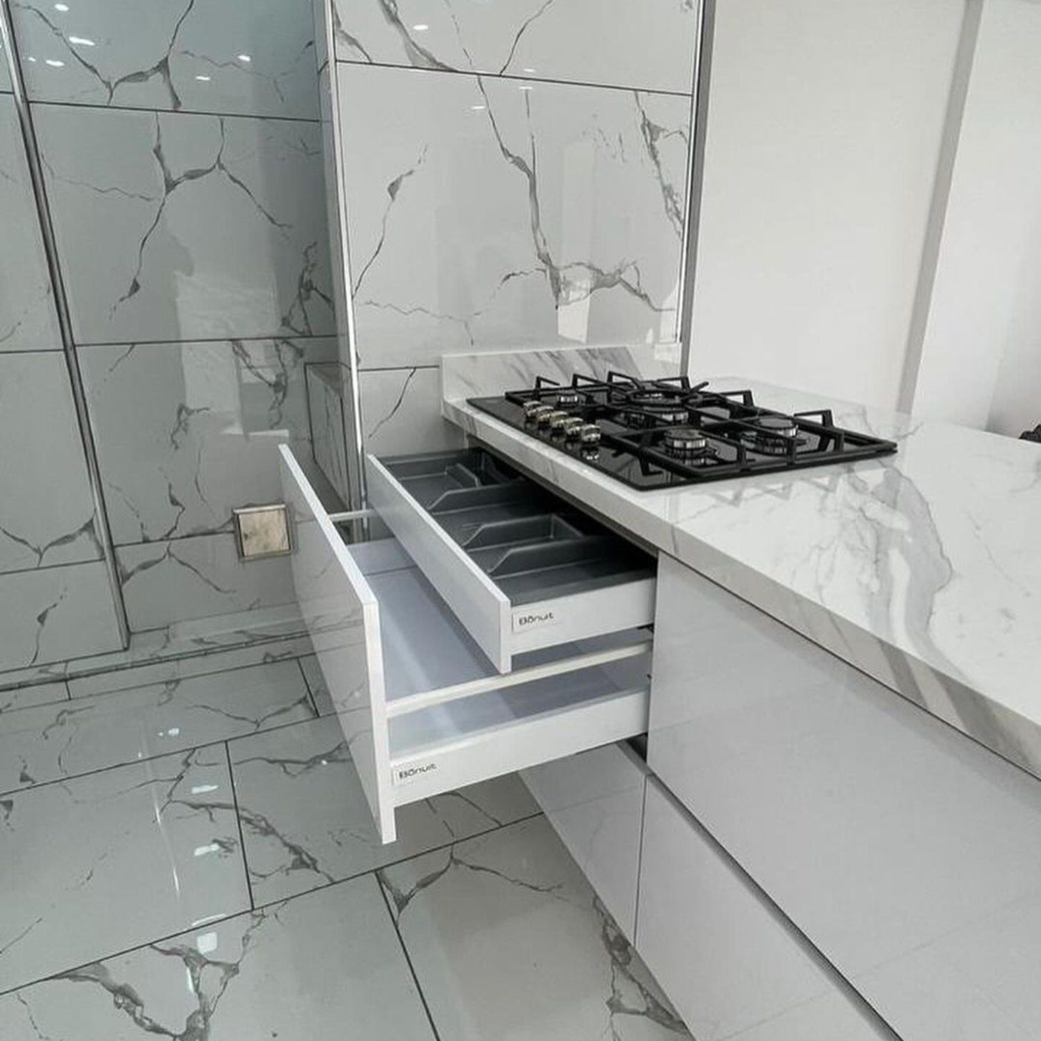 A modern kitchen featuring efficient space utilization with an integrated gas cooktop and marble-style tiles