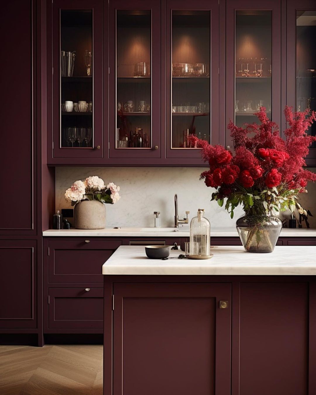 A kitchen with deep burgundy cabinets and a marble countertop