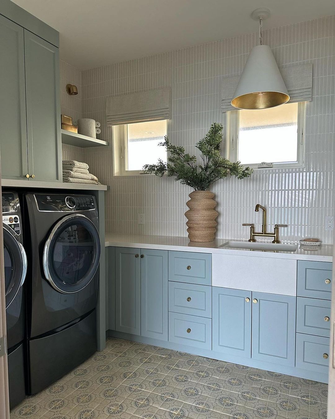 A serene laundry room with pastel blue cabinetry, and patterned floor tiles