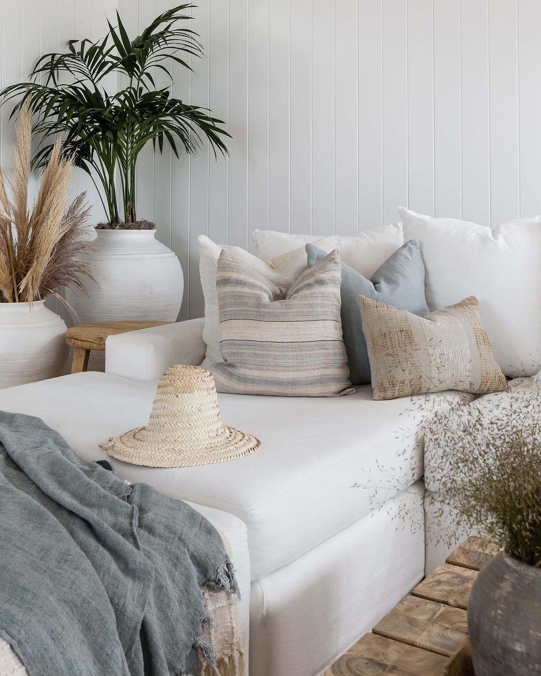 A cozy and inviting living room corner with a stylish straw hat on a white couch