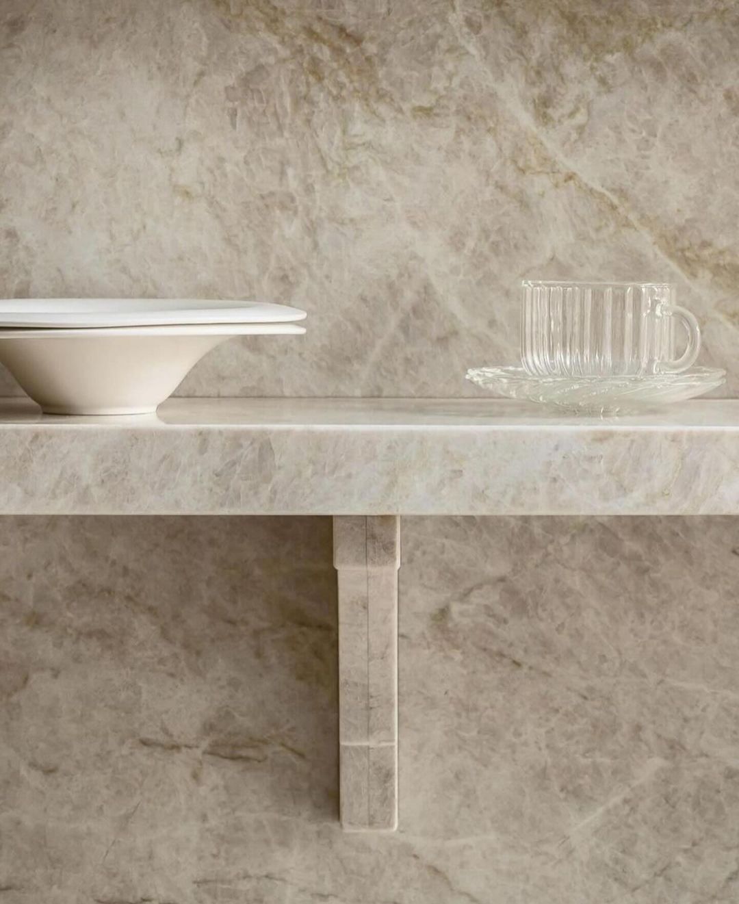 An aesthetically pleasing shelf display contrasting the smoothness of porcelain and glass against a marbled backdrop