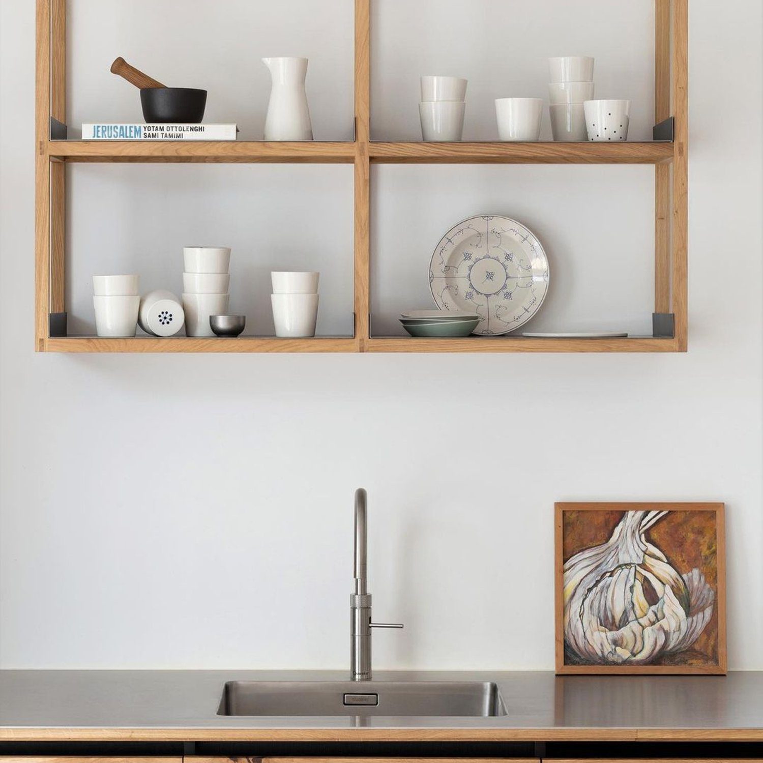 A minimalist kitchen design featuring open wooden shelves, a sleek undermount sink and modern cabinetry