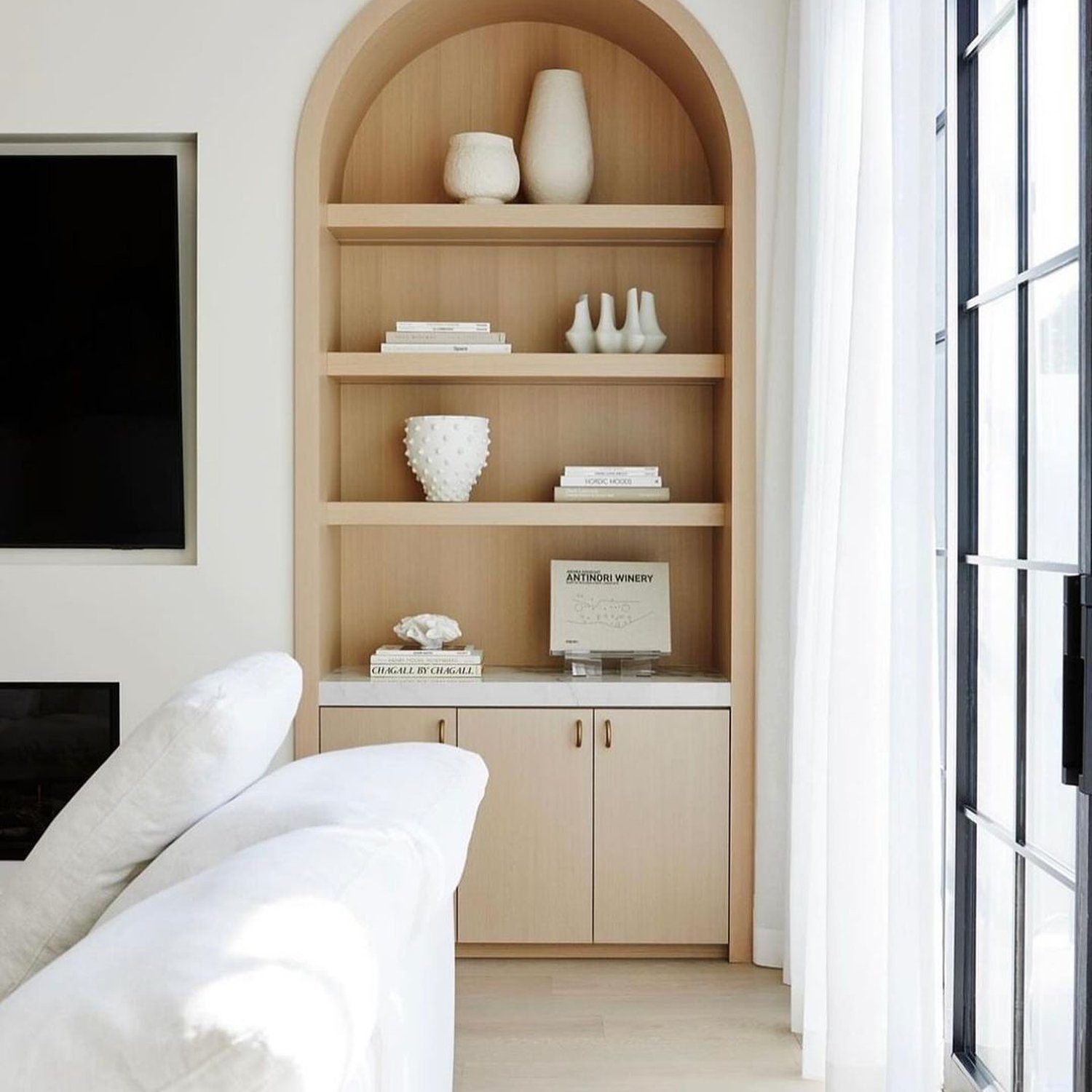 A stylish and minimalist living room shelving design with arched top