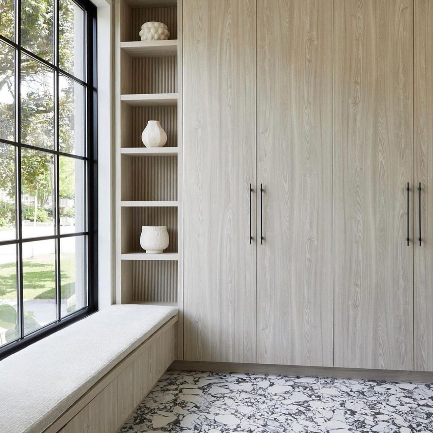 A serene reading nook featuring a cushioned window bench and built-in shelves with minimalist decor