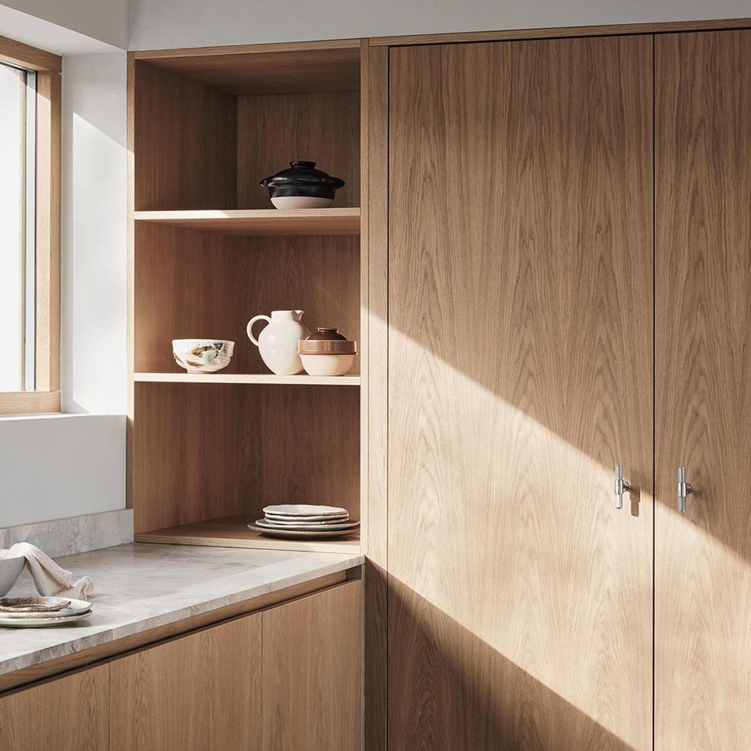 A minimalistic kitchen corner featuring warm wooden cabinetry and open shelving