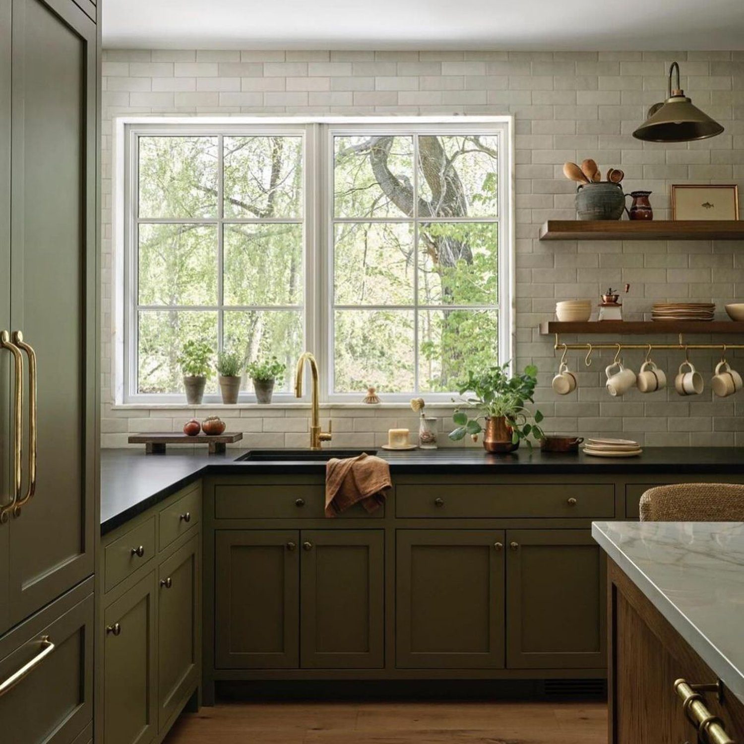 A serene kitchen with olive green cabinetry and marble countertops