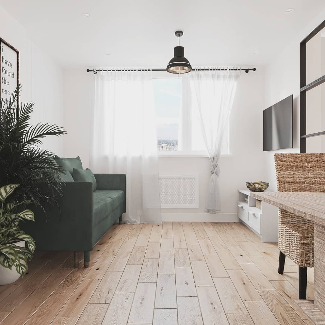 A modern and inviting living room space featuring a plush green sofa, a large bright window draped with sheer curtains, a sleek black floor lamp, and refreshing greenery enhancing the cozy atmosphere.