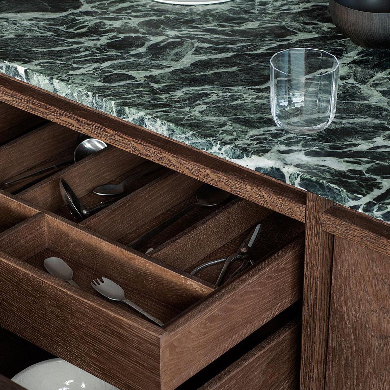 Elegantly organized kitchen drawer with dark wood finish and green marble countertop