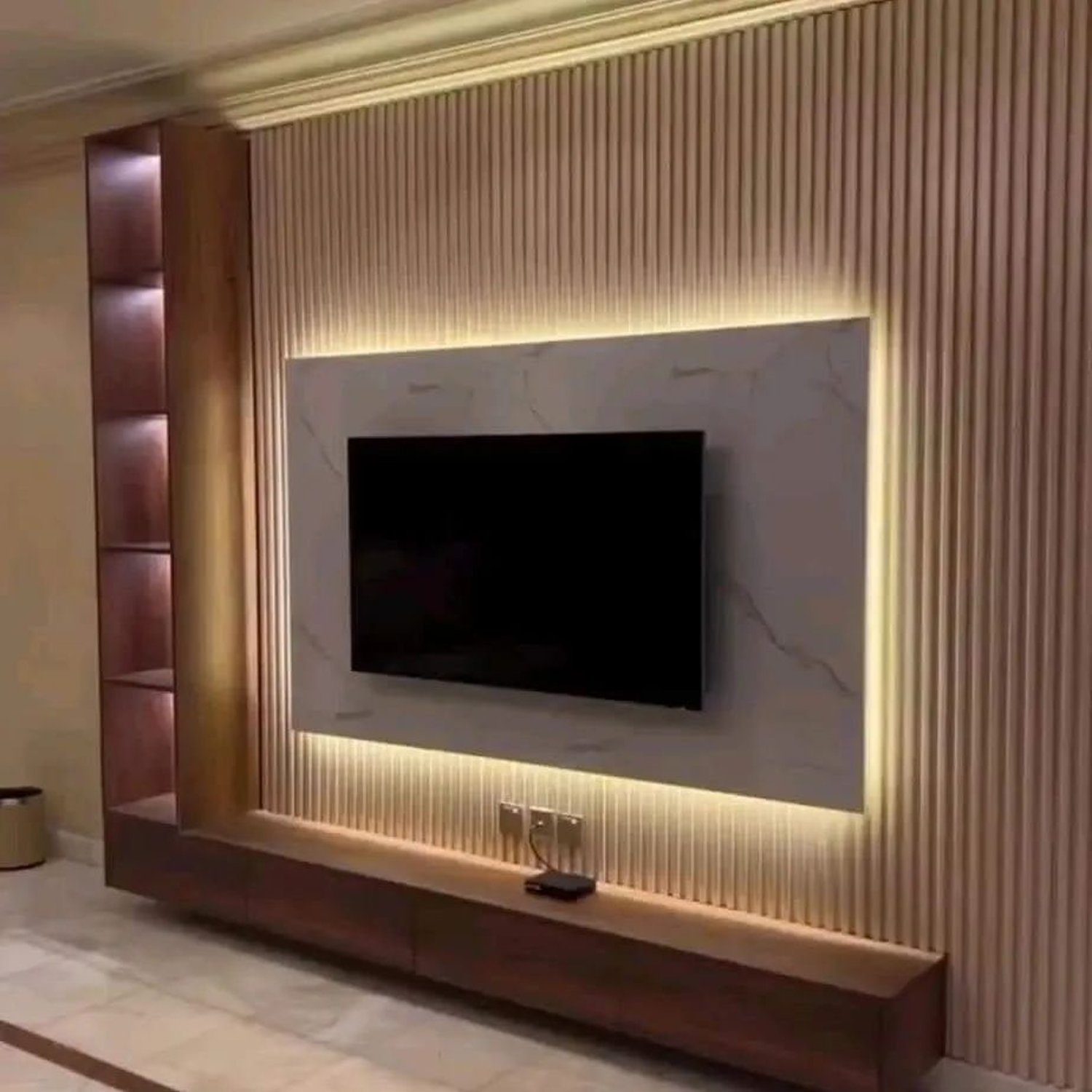 Elegant interior design featuring a mounted television within a marble-framed inset, complemented by vertical fluted panels and warm lighting accents.