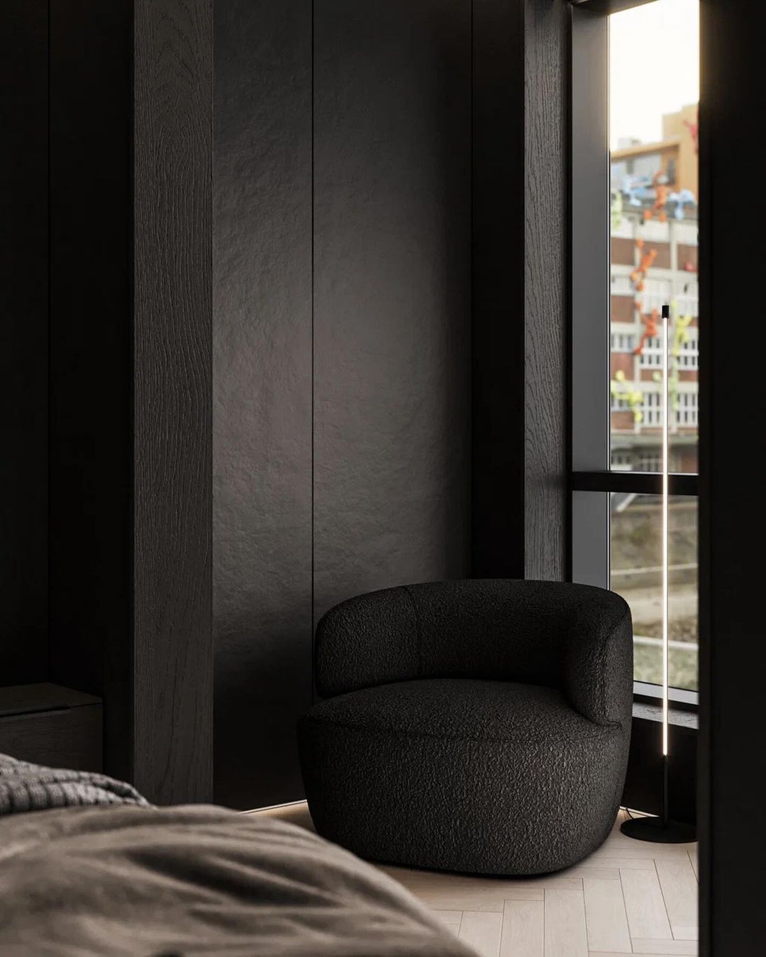 A cozy modern corner with an oversized textured black armchair by a large window