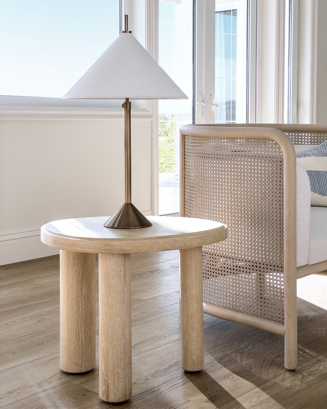 A tastefully composed corner featuring a minimalist wooden side table and a classic floor lamp with a conical shade.