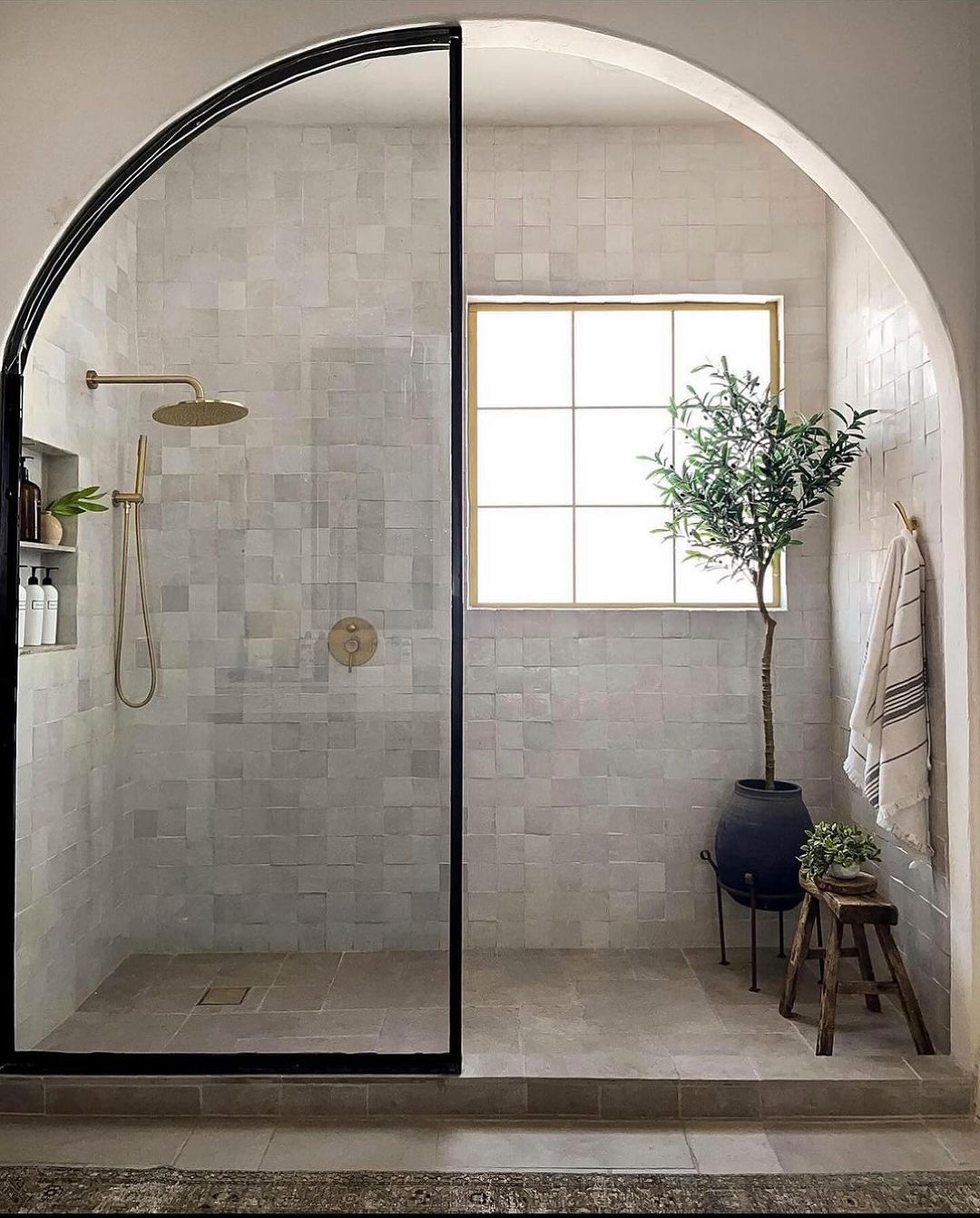 A minimalist bathroom with an arched glass shower enclosure