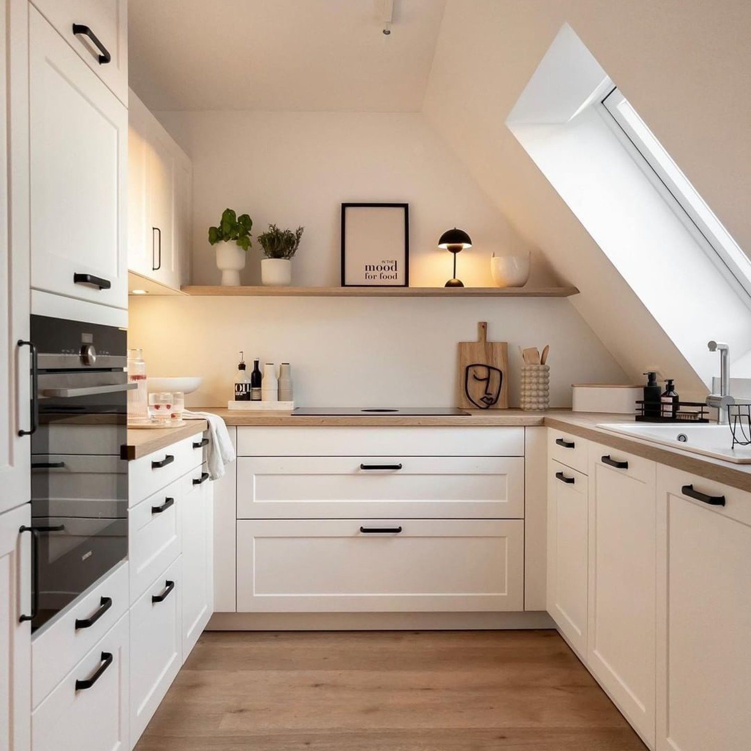 A modern attic kitchen with skylights and white cabinetry