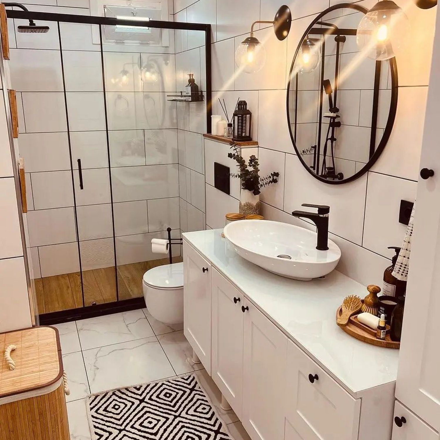 A modern white tiled bathroom featuring a sleek design with black accents, an oval vessel sink, and striking round mirror.