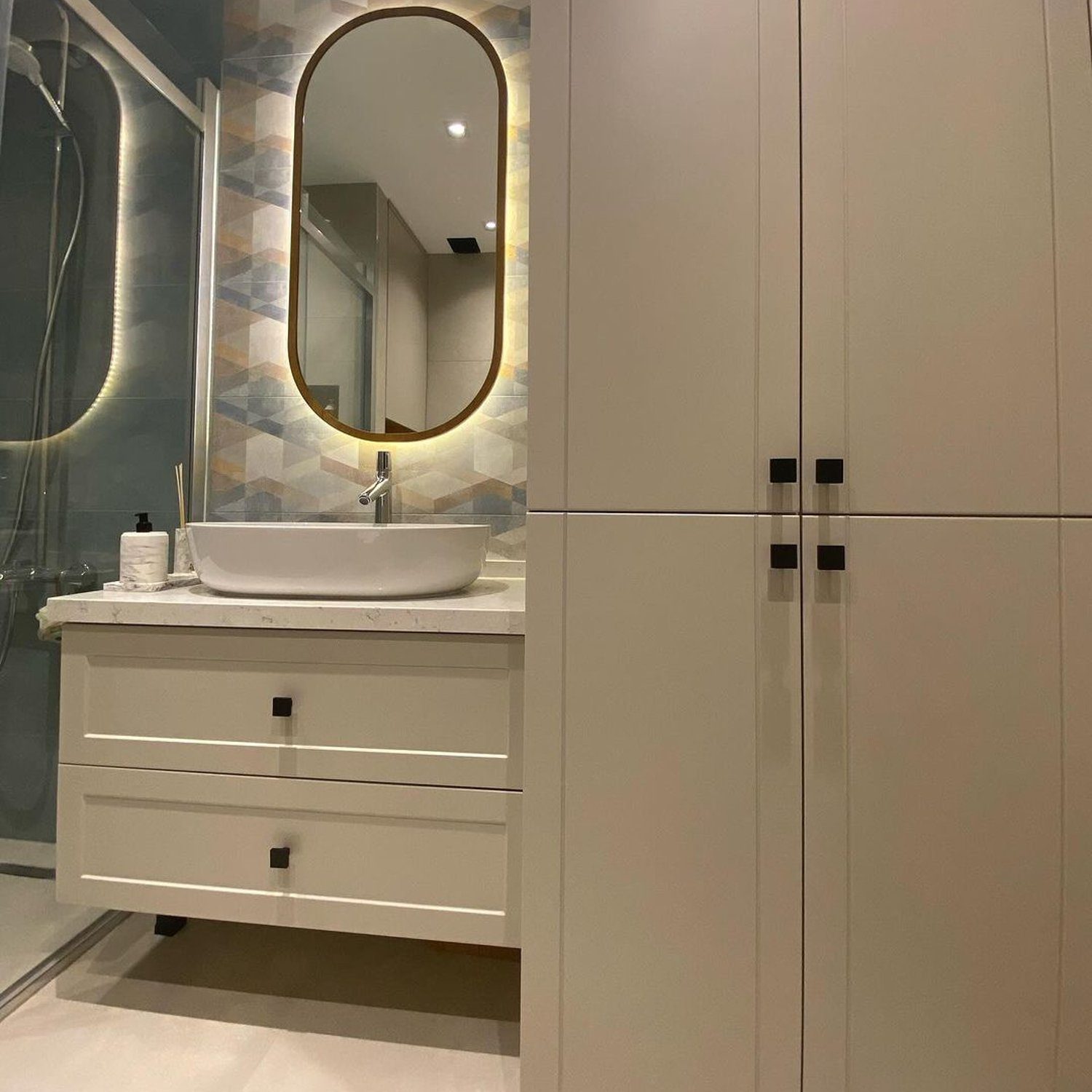 A modern bathroom featuring a sleek vanity unit and a tall storage cabinet