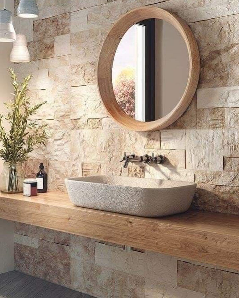 A modern bathroom featuring a stone wall, wooden shelf vanity, and stone vessel sink