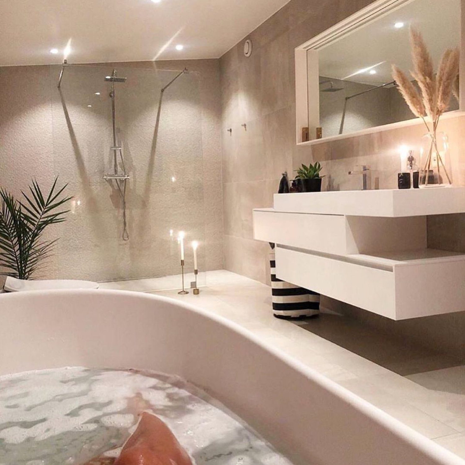 A modern bathroom featuring a free-standing bathtub, sleek shower space, and minimalistic vanity.