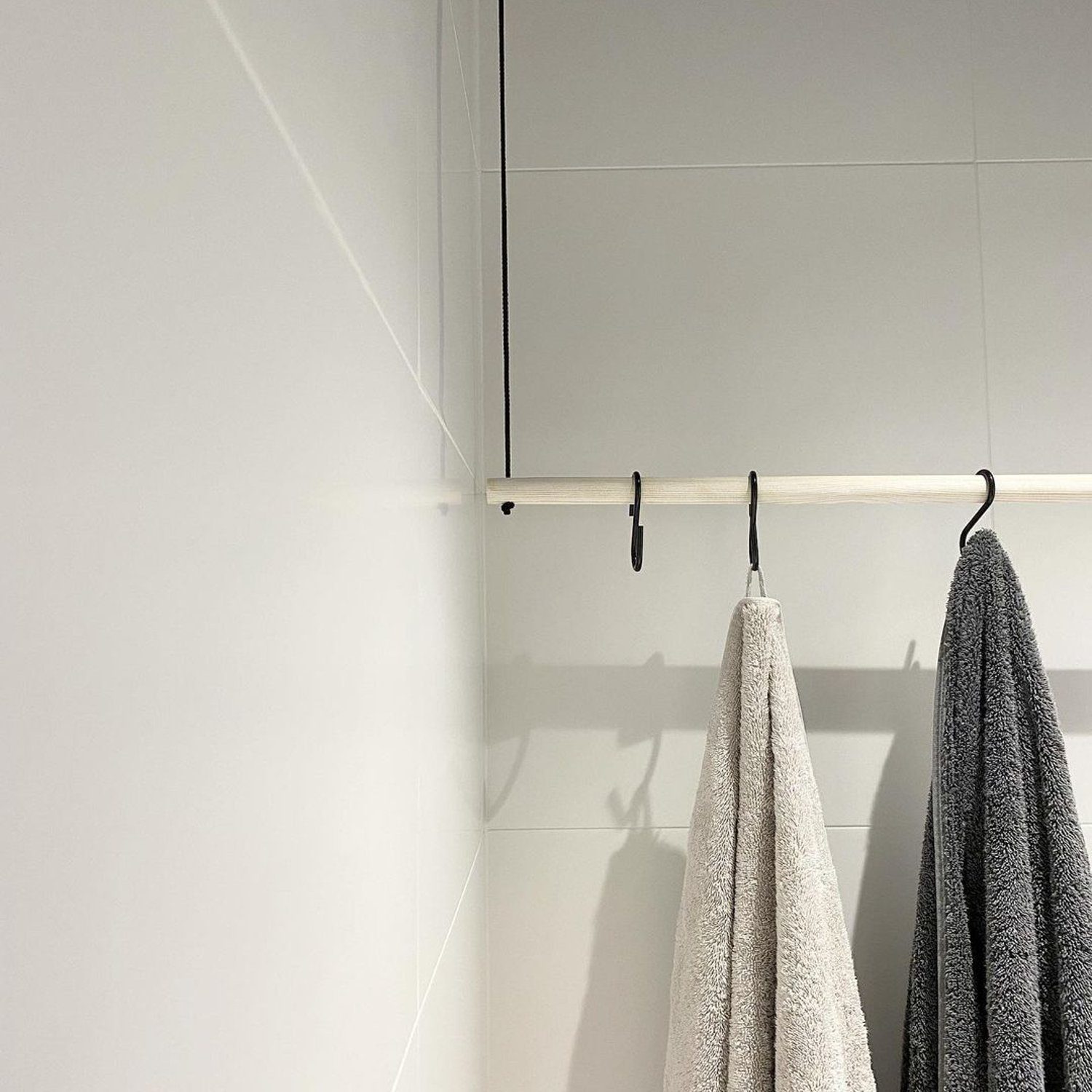 A minimalist bathroom design featuring two towels hanging on a sleek metal rail