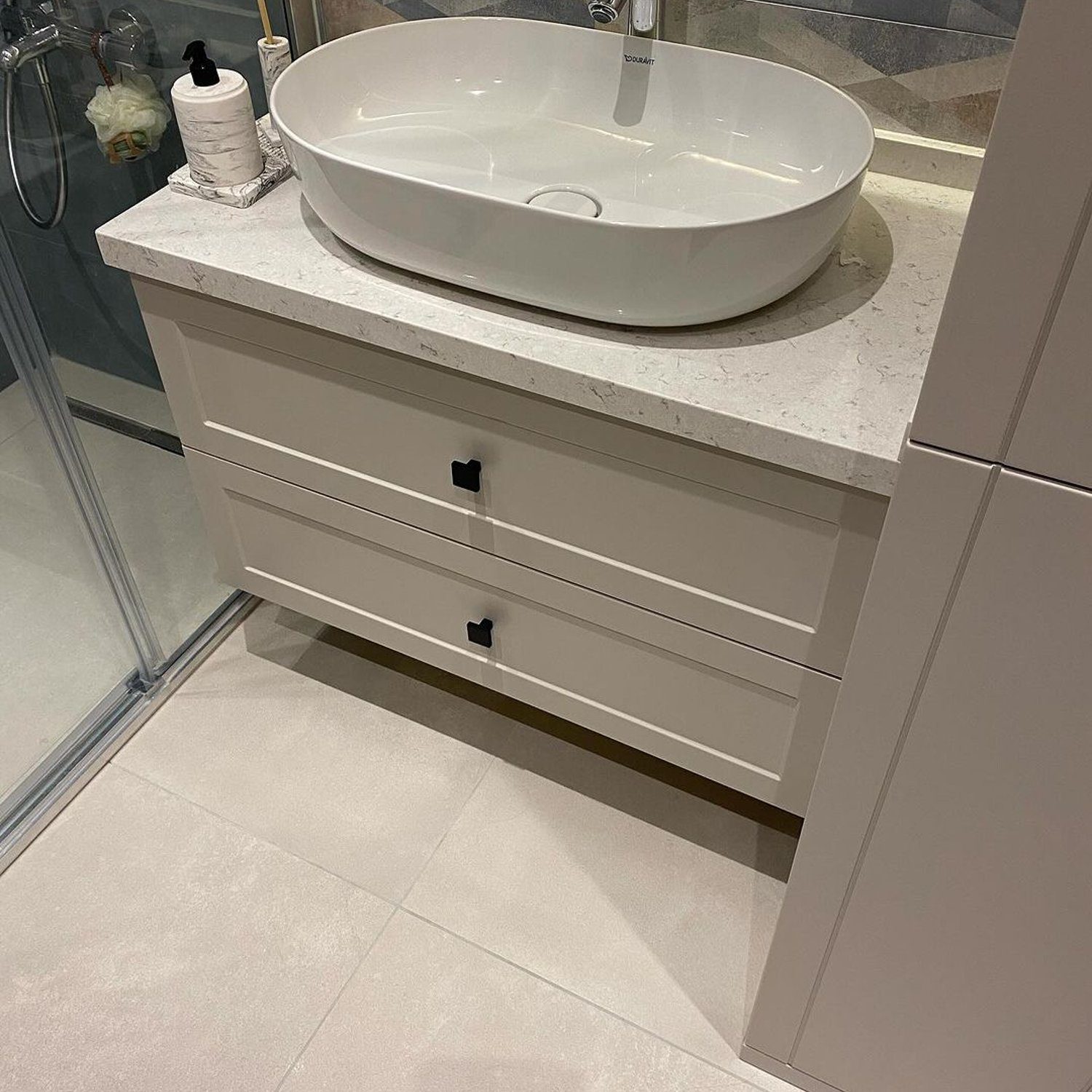 A minimalist bathroom featuring a round vessel sink on a sleek vanity with stone countertop