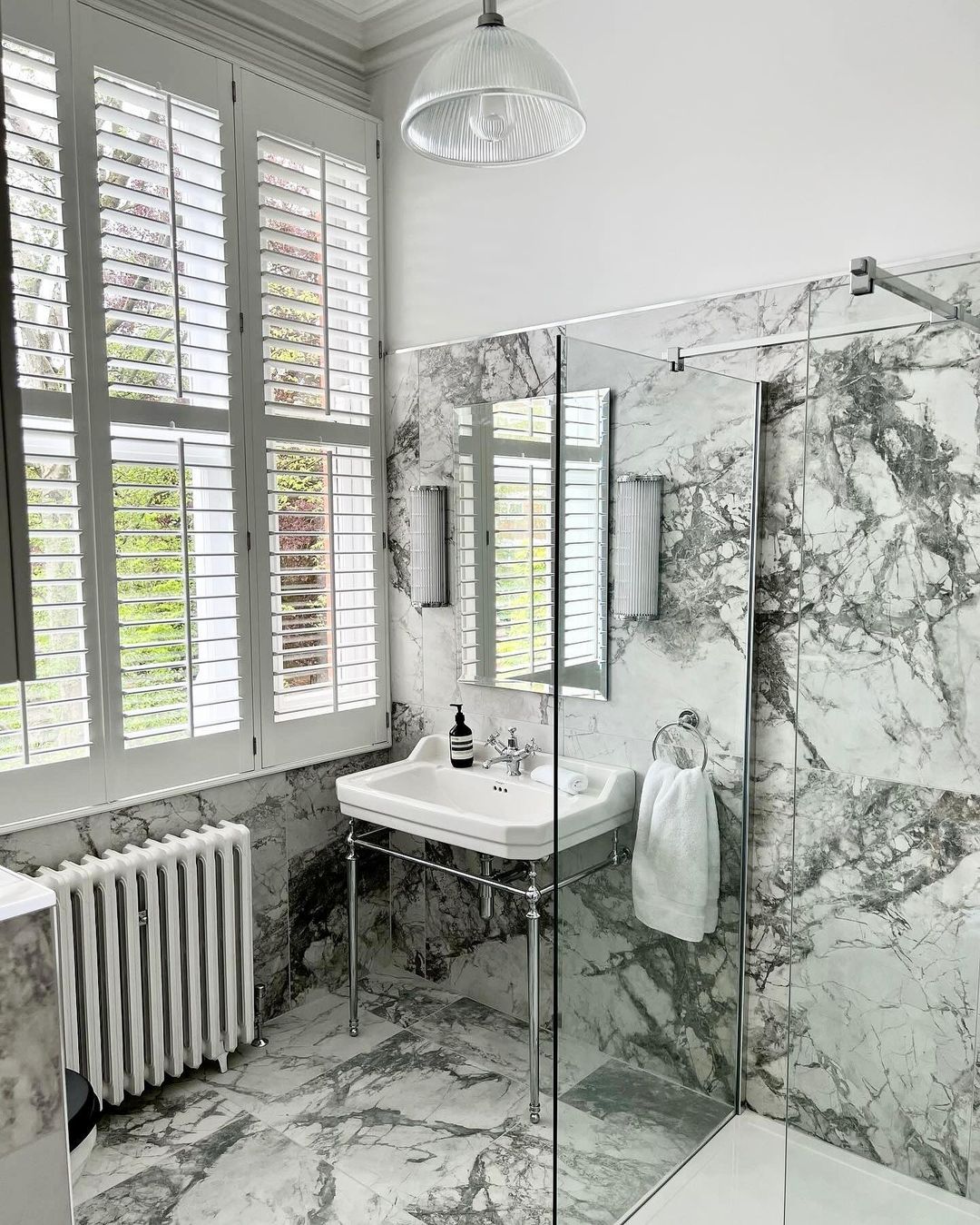 Stylish marble-clad bathroom with modern fixtures