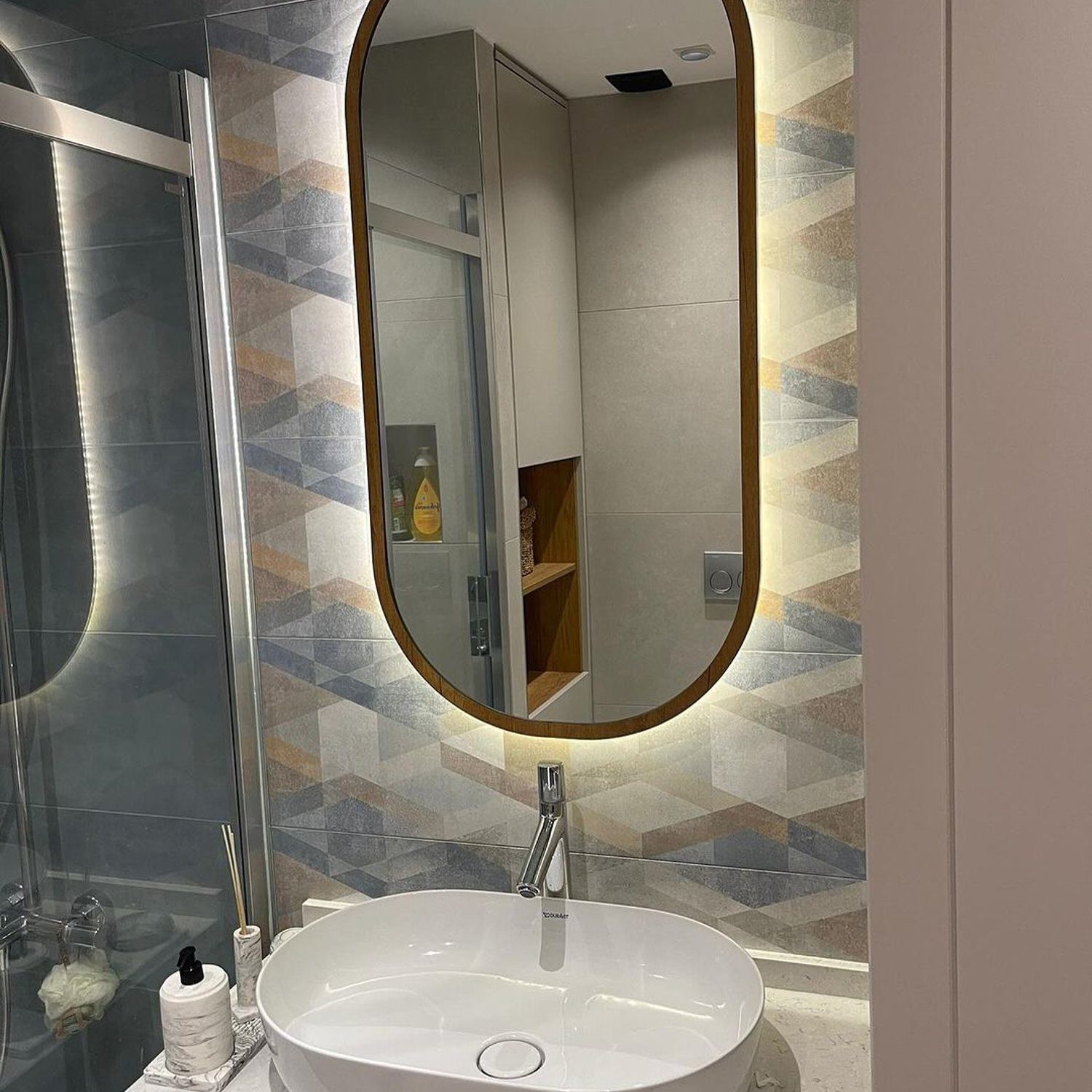 Elegant bathroom featuring a unique mirror and textured tiles