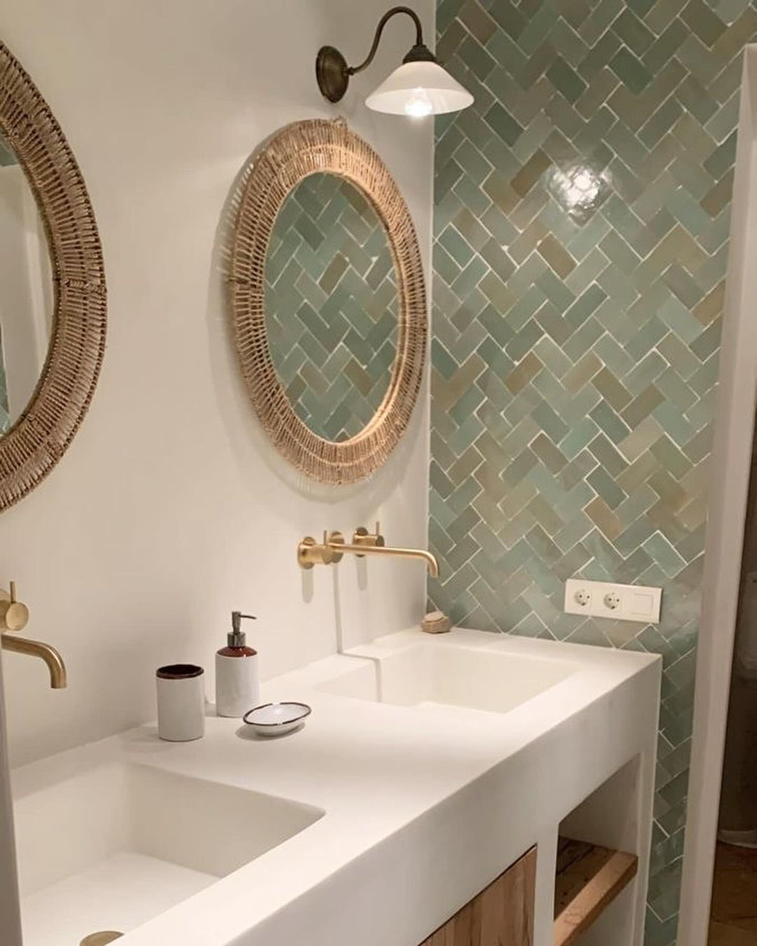 A modern bathroom with woven mirrors and herringbone tile