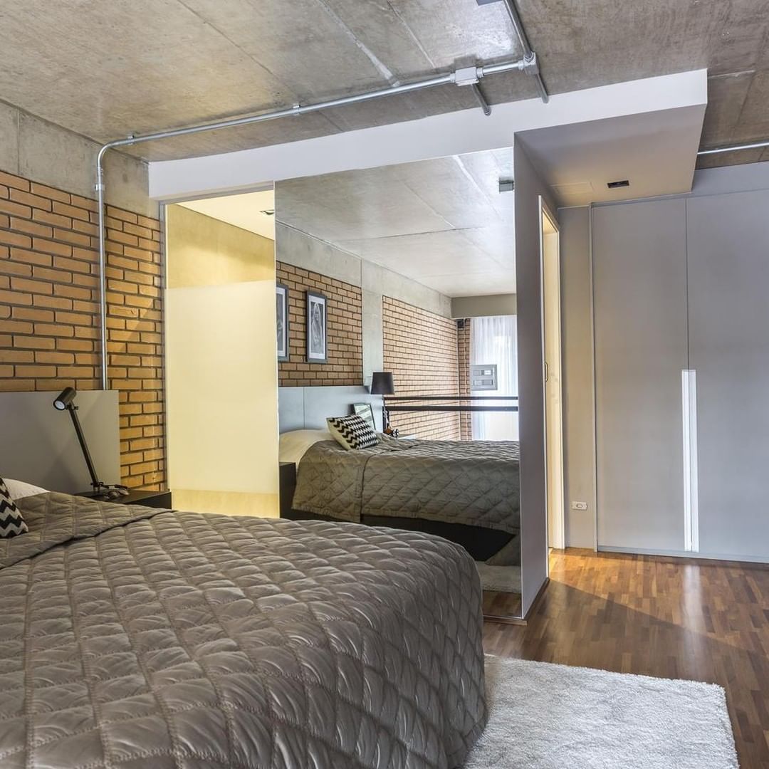 Contemporary bedroom with exposed concrete ceiling and brick walls