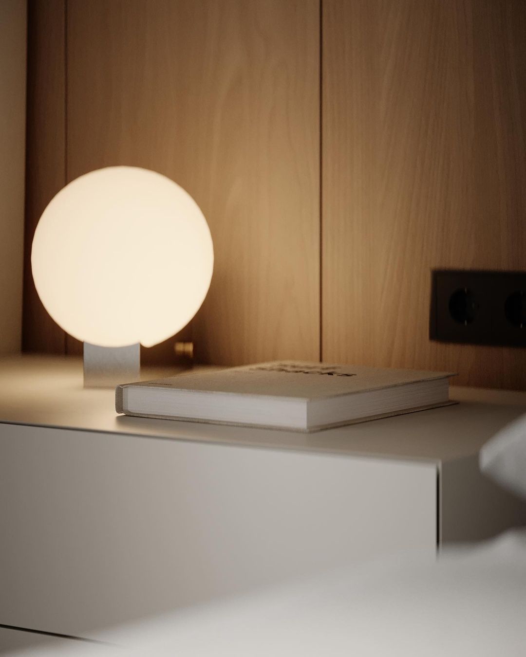 A modern lamp illuminating a book on a nightstand