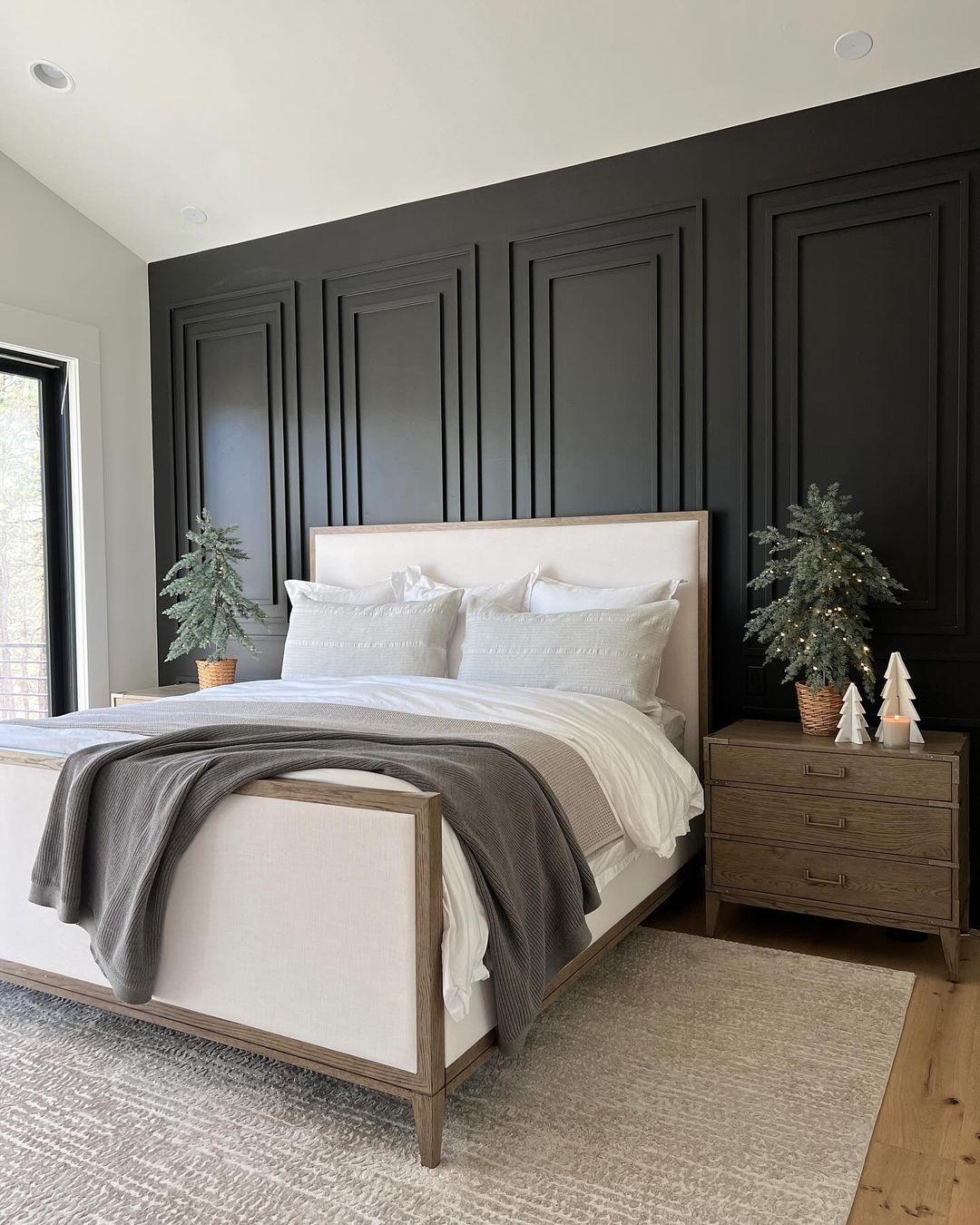 A modern and chic bedroom featuring a bold black accent wall with geometric paneling