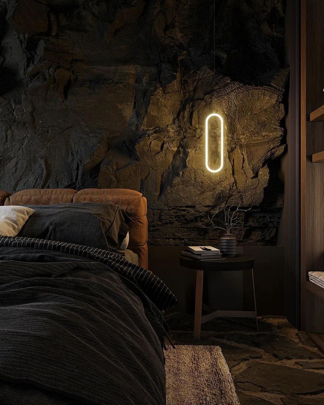 A modern bedroom featuring a rugged rocky wall backdrop, a plush velvet bed, and a sleek, oval-shaped hanging light.