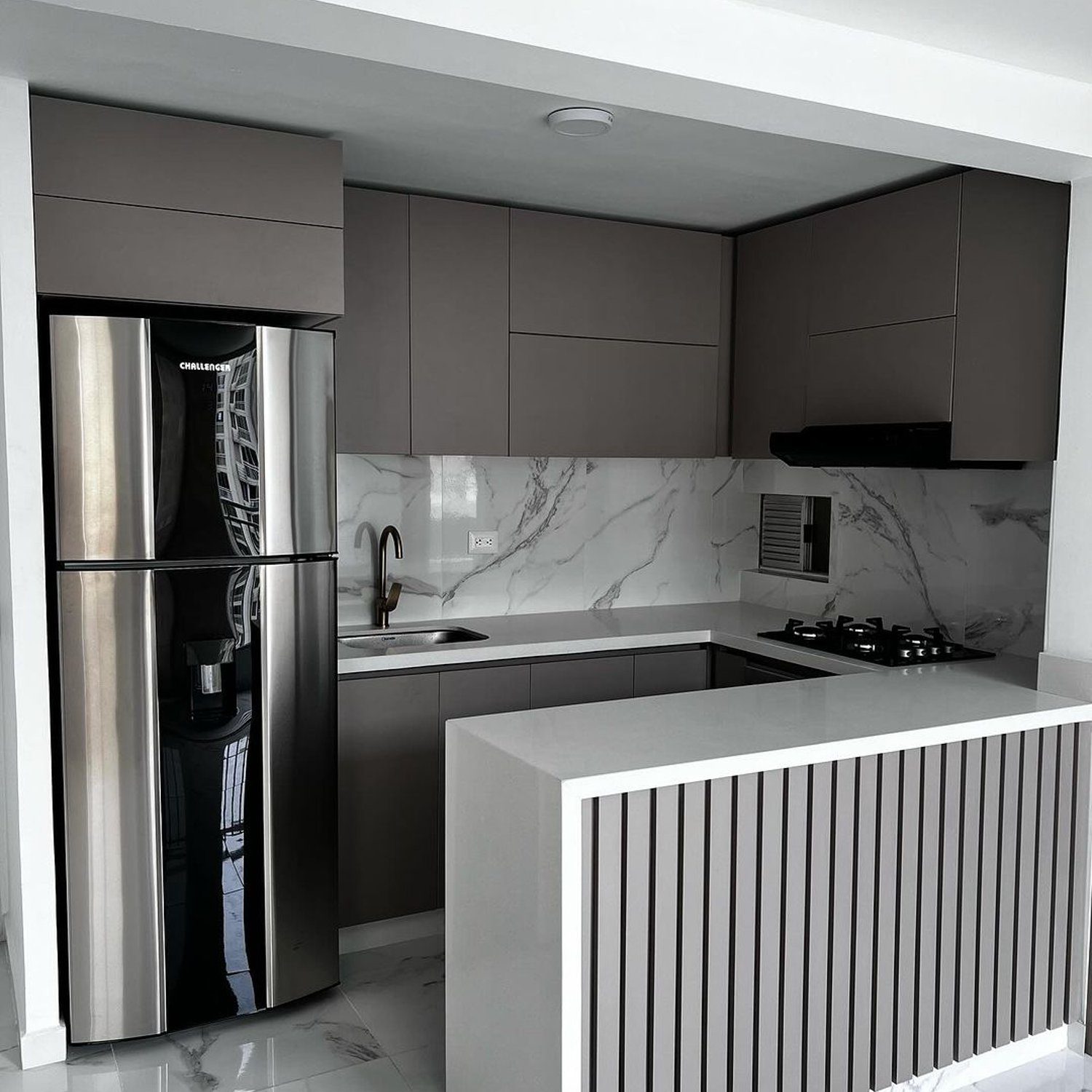 Elegant and modern kitchen featuring dark gray cabinets, marble backsplash, and a stainless steel refrigerator