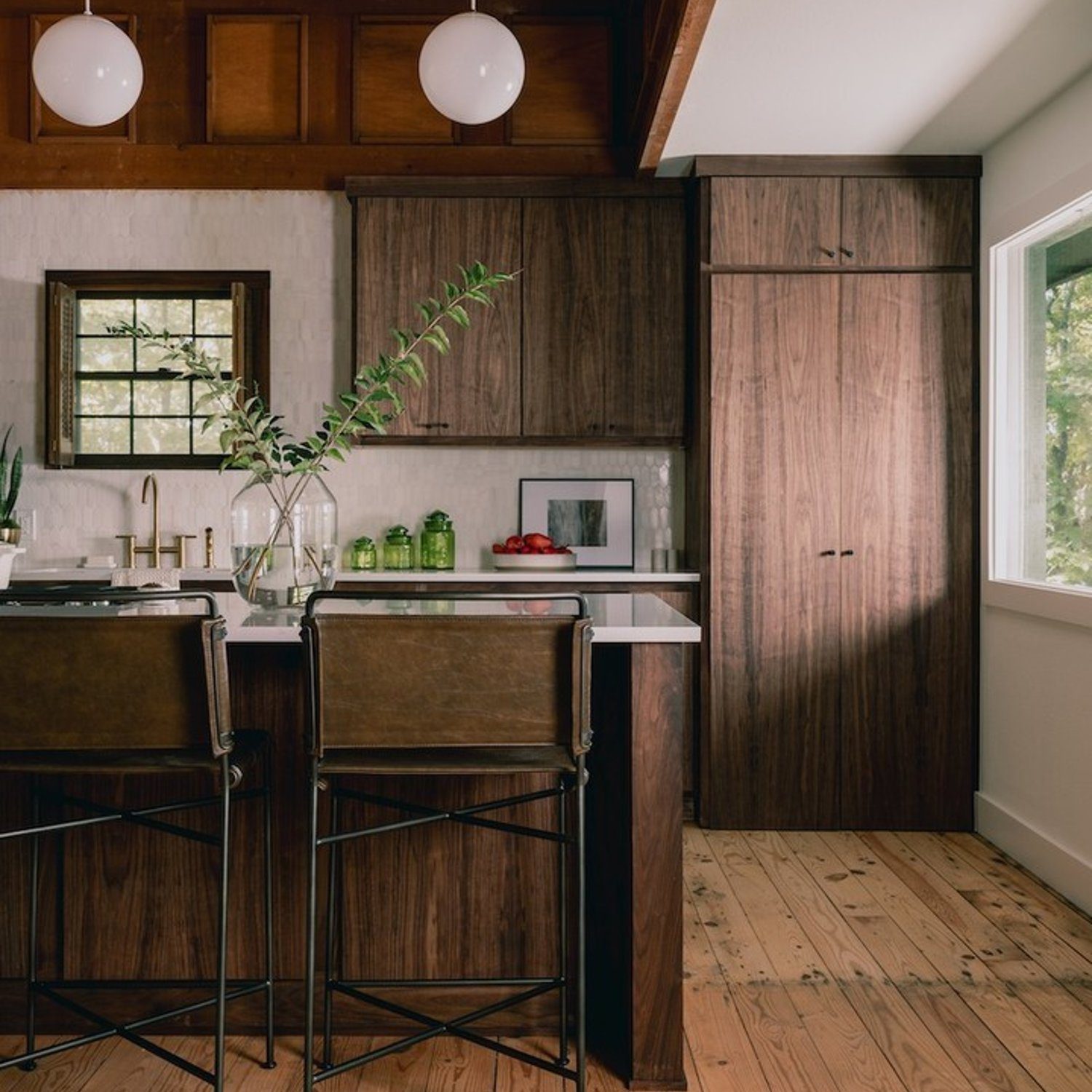 A modern kitchen featuring rich dark wood cabinets and a contrasting white countertop, with brass fixtures adding a touch of elegance