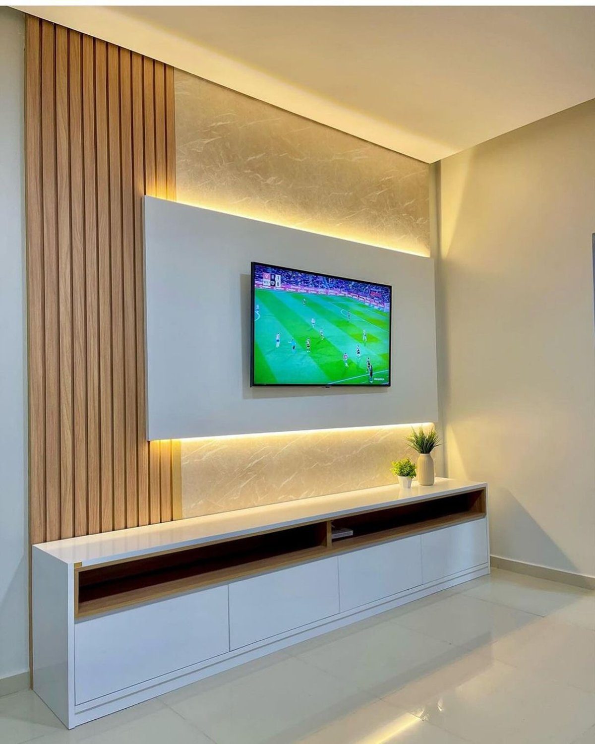 A modern entertainment space featuring a flat screen TV on a wood and white stone accented wall with ambient lighting