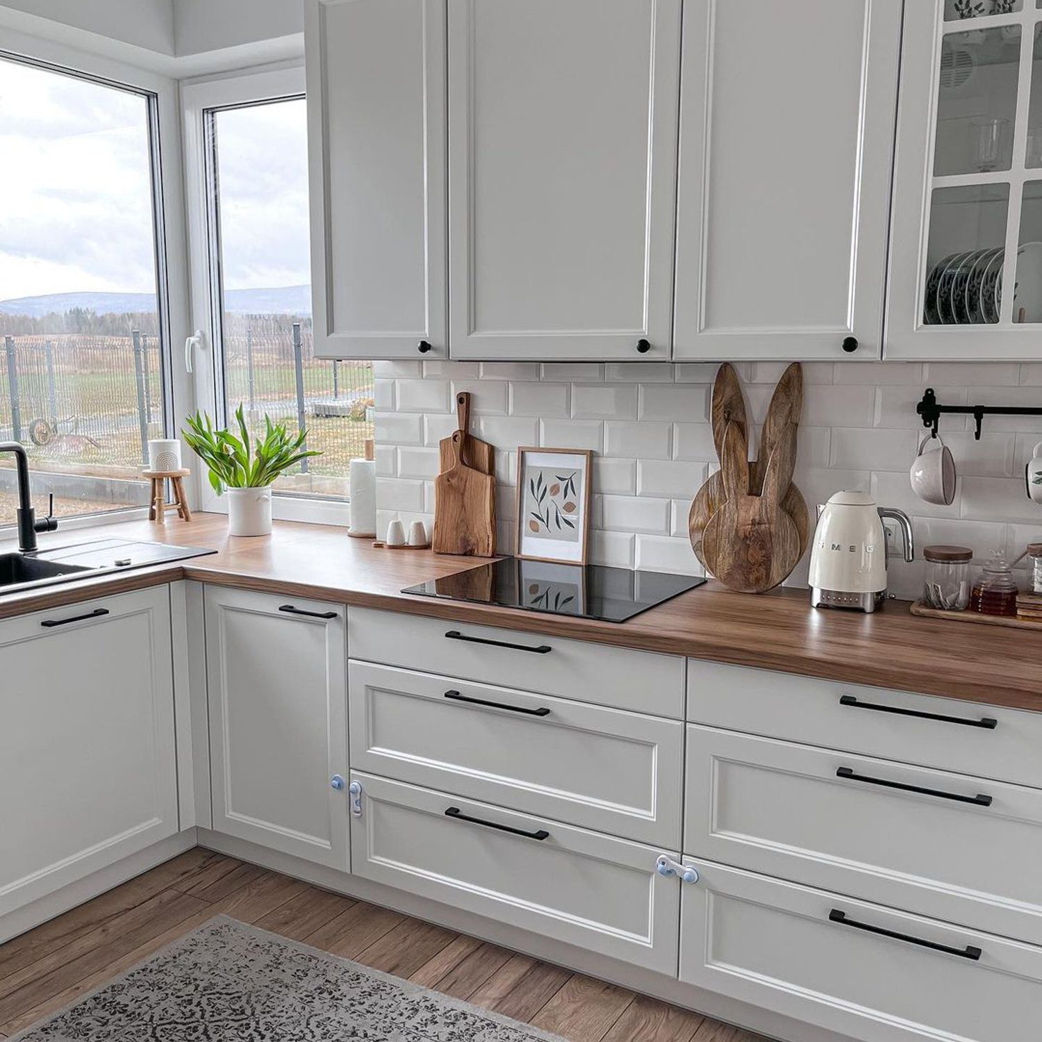 A stylish kitchen showcasing a harmonious blend of white cabinetry and subway tiles with wooden countertops and modern pulls.