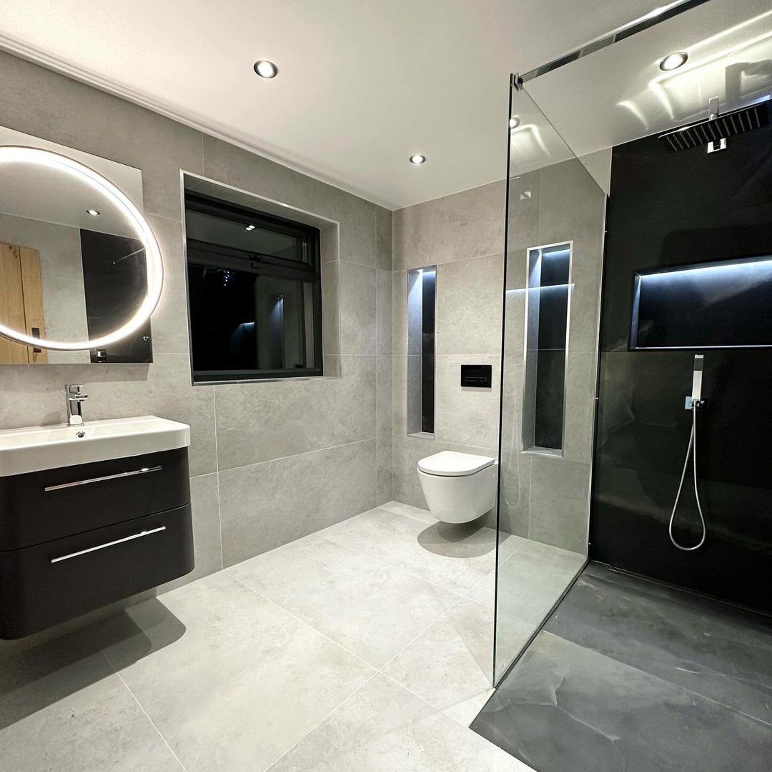 A modern, sleek bathroom featuring a monochromatic grey palette with strategic lighting accents